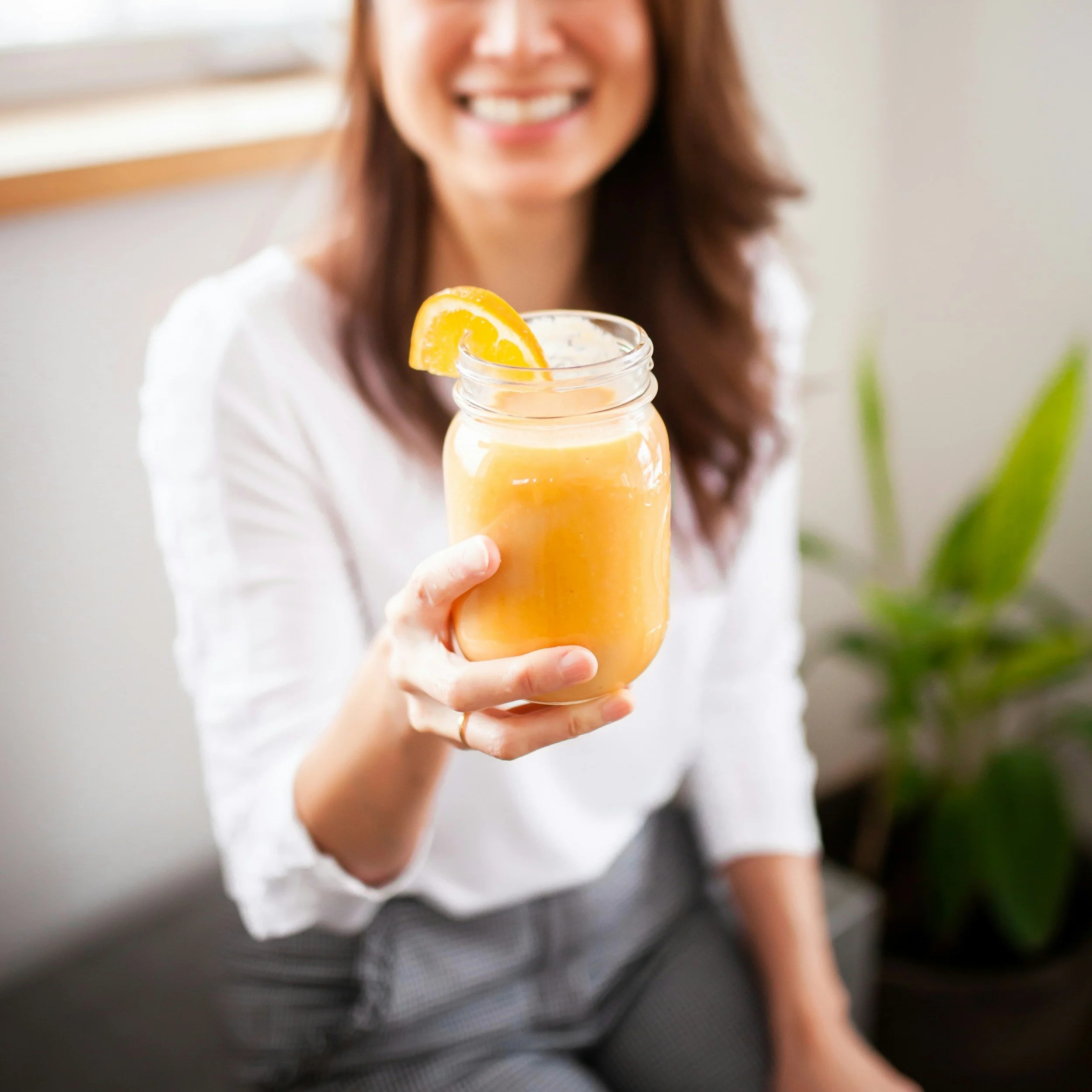 Woman smiling while holding a jar of nutritious drink representing healthy lifestyle and nutritional wellbeing