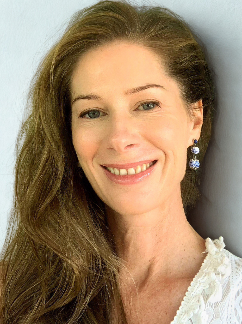 Portrait of naturopath and nutritionist Gina King smiling, wearing earrings and a white blouse.