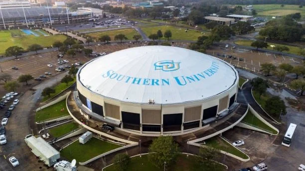 Aerial view of a round building with 'Southern University' written on the roof, surrounded by parking lots, green areas, and trees.