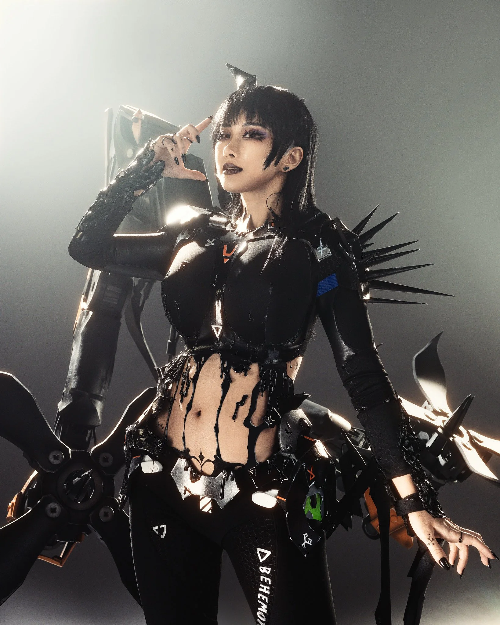 A woman wearing a futuristic, black, cyberpunk-style outfit with spikes and mechanical accessories, striking a confident pose.