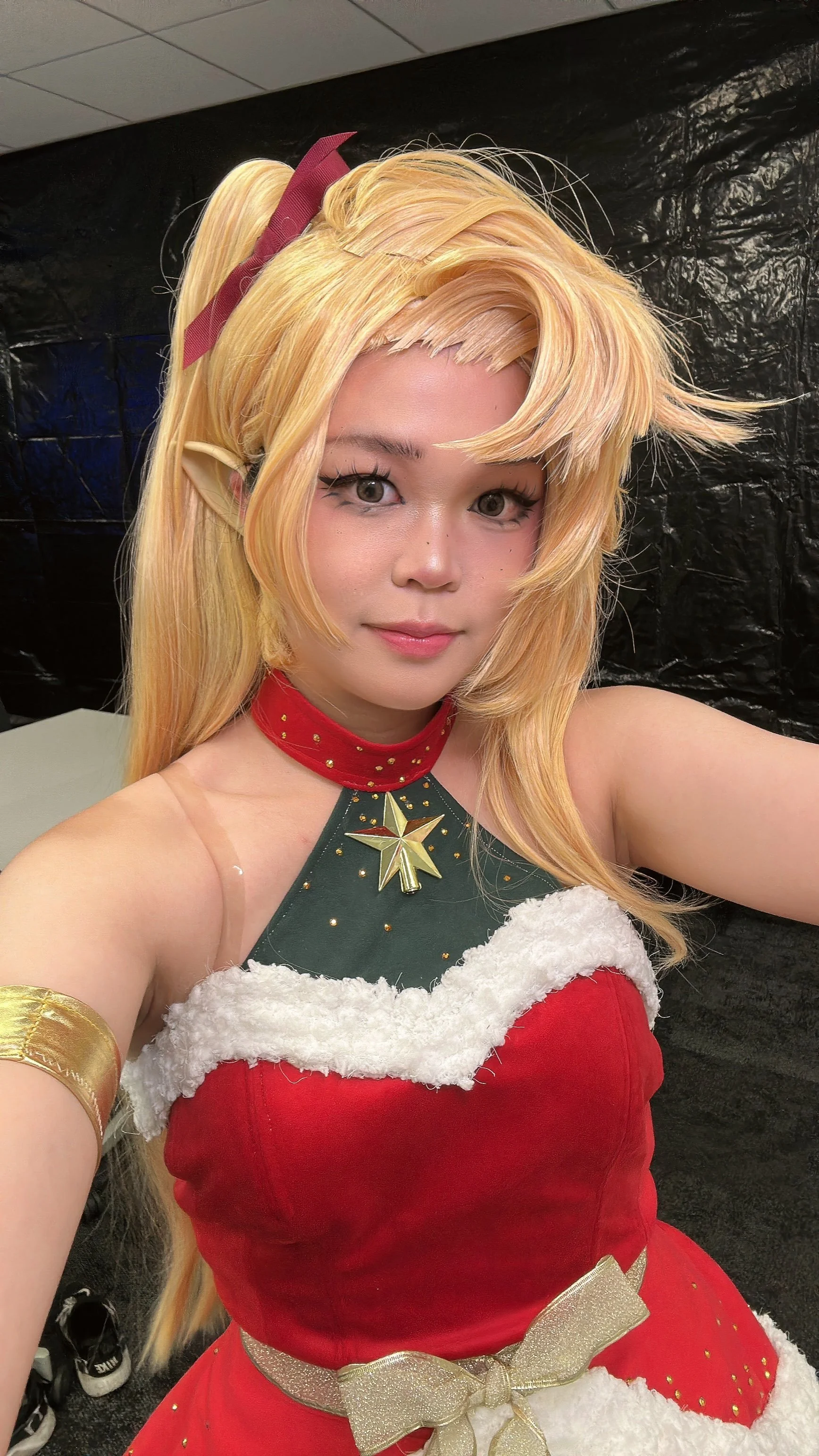 Person dressed in a Christmas-themed costume with blonde wig, elf ears, and festive accessories, taking a selfie.