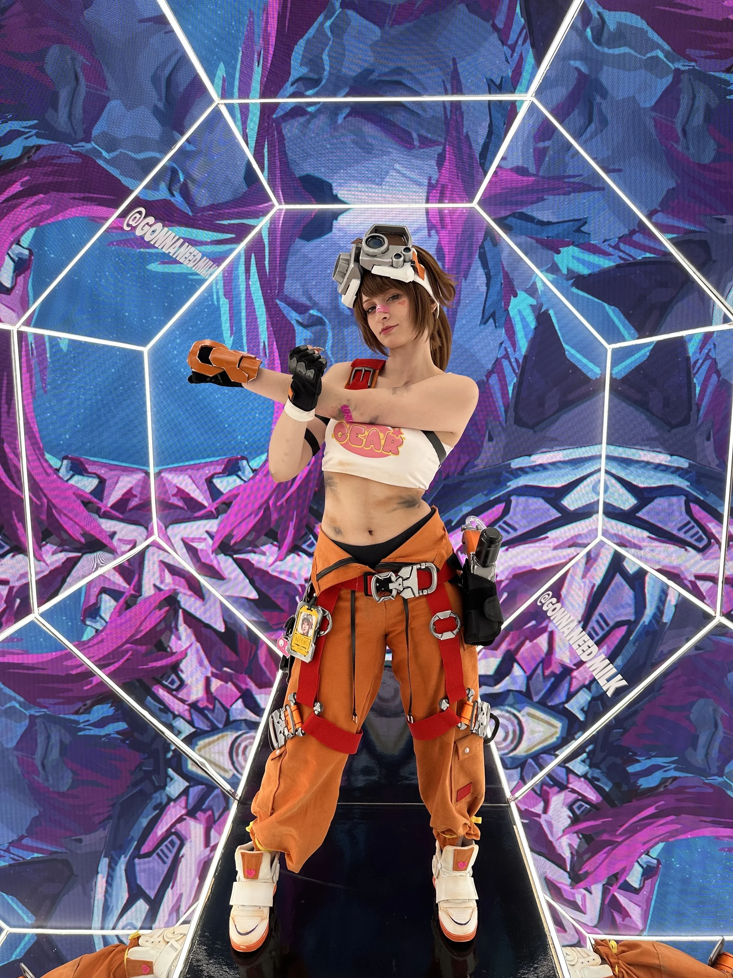 A woman dressed as the video game character Overwatch's Tracer in an exhibition with a digital artwork background