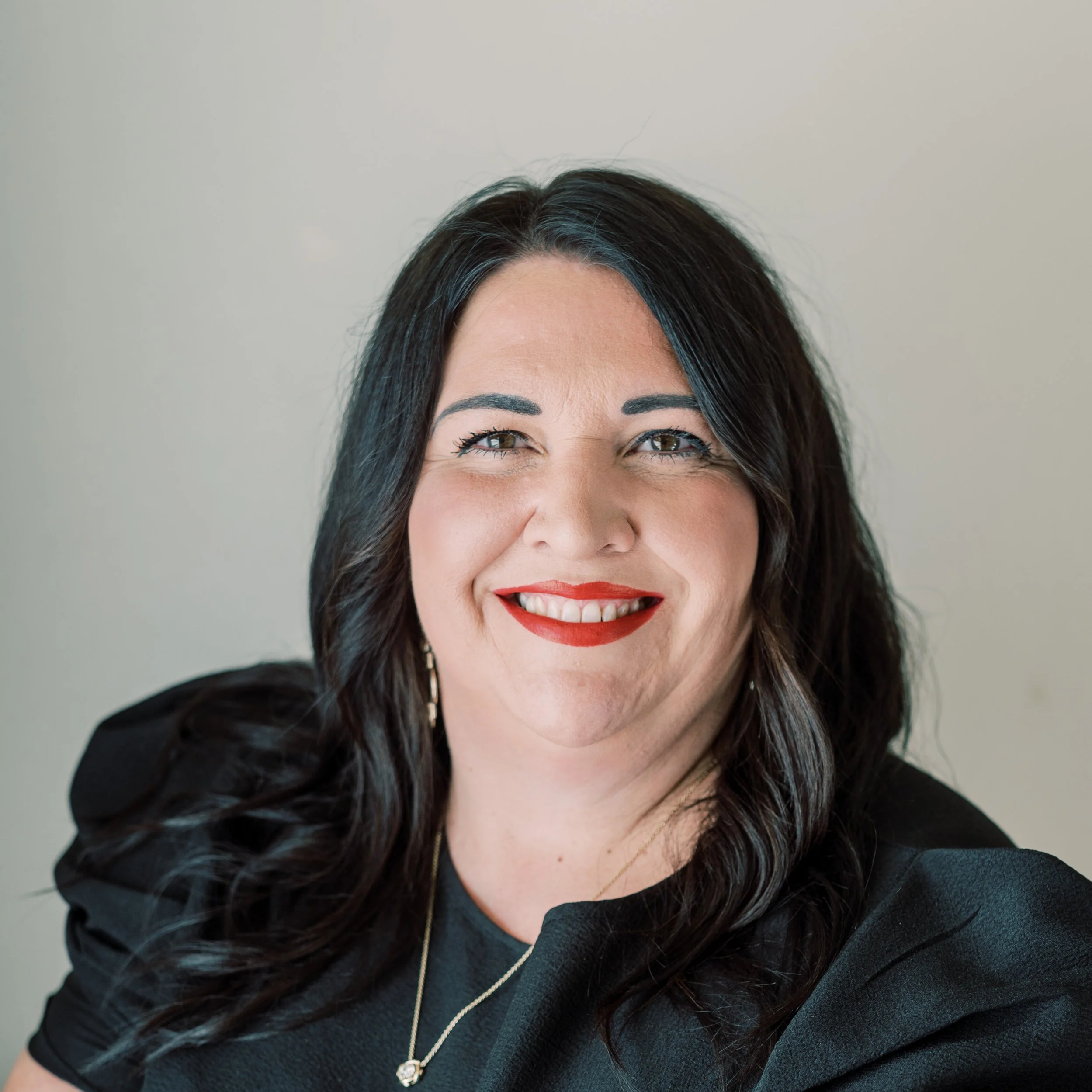 Headshot of HollyAnn Petree in a black blouse with a gold necklace and earrings