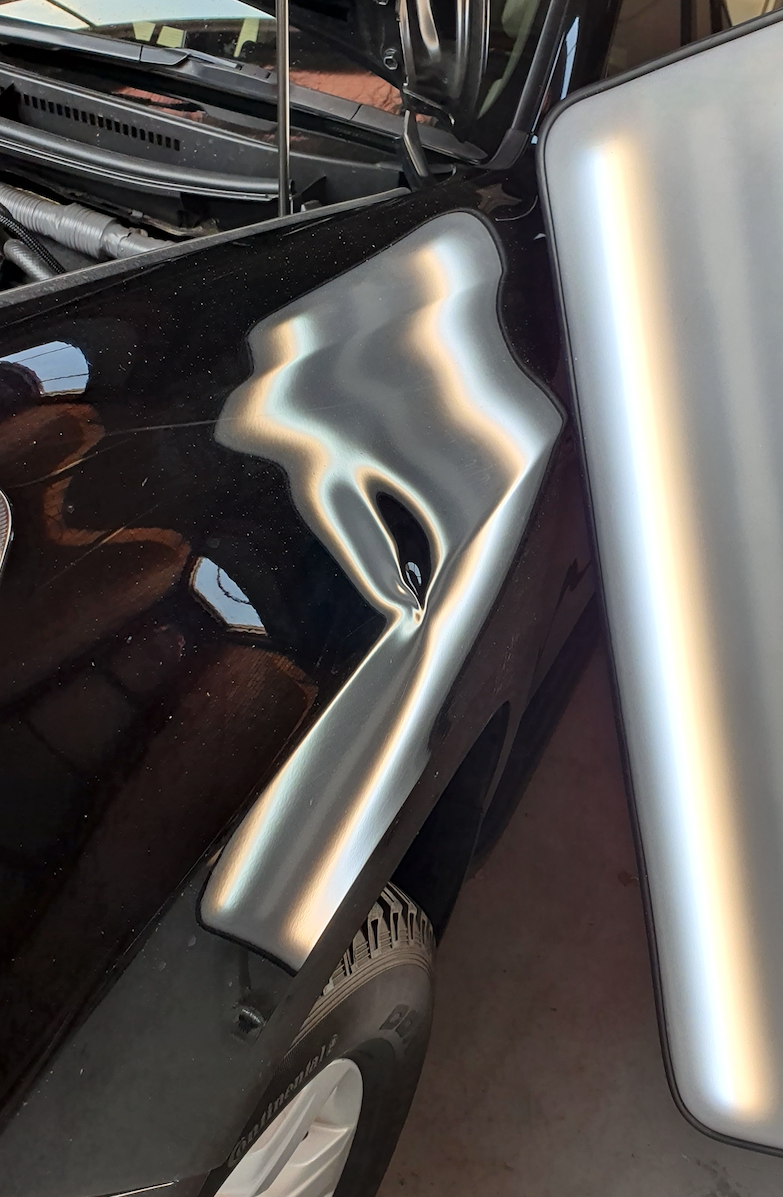 Before — Deep front guard dent shown clearly under a PDR inspection light.