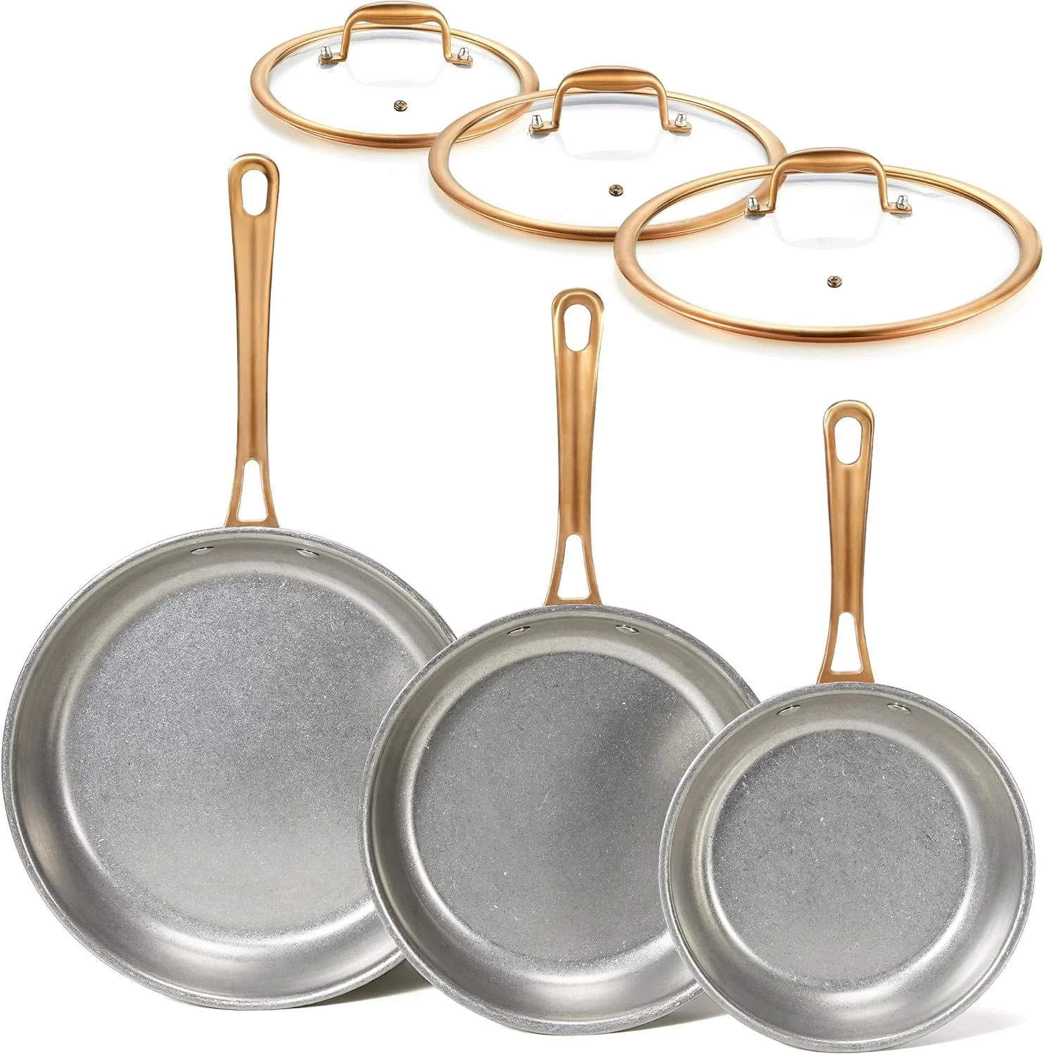 A set of three frying pans with copper-colored handles, placed in front of three glass lids with copper-colored rims and handles.