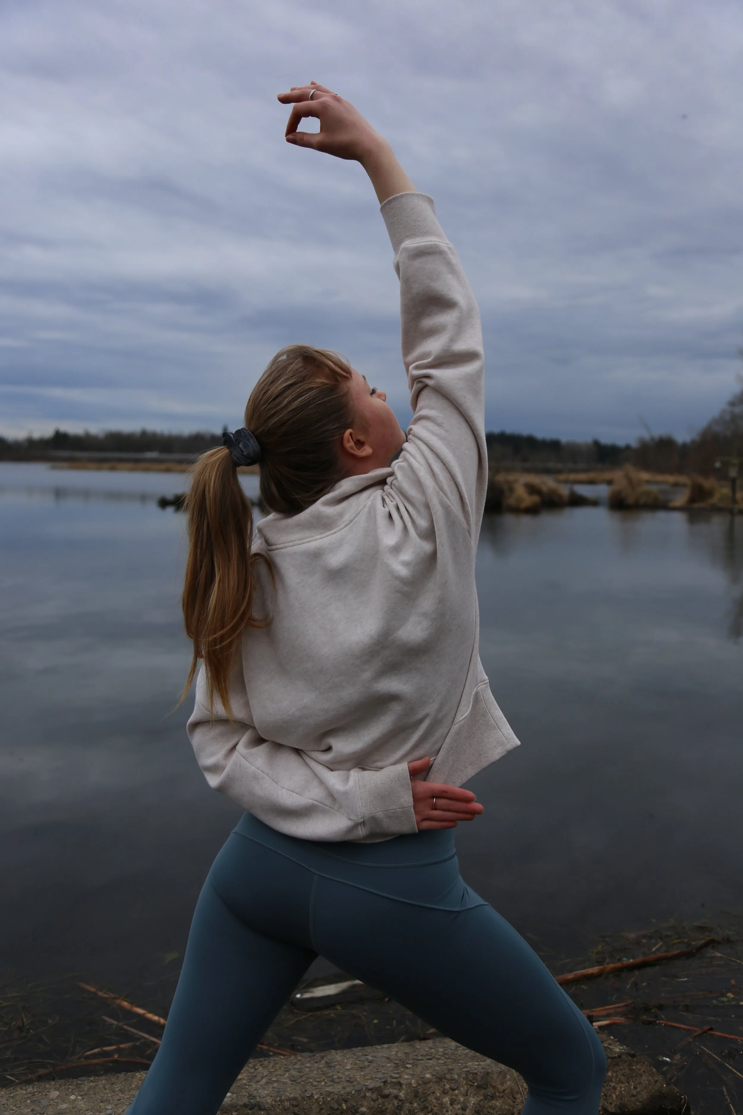 A woman practicing yoga outdoors on Lake Washington on a cloudy day.