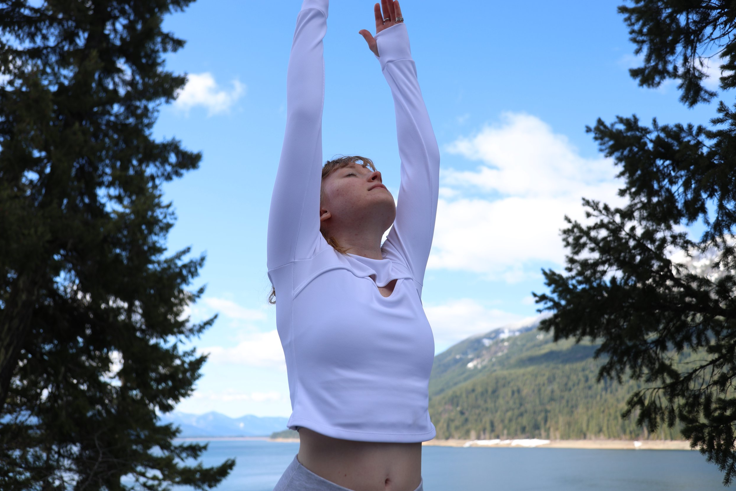 A young woman practicing yoga outdoors by Lake Kachess.