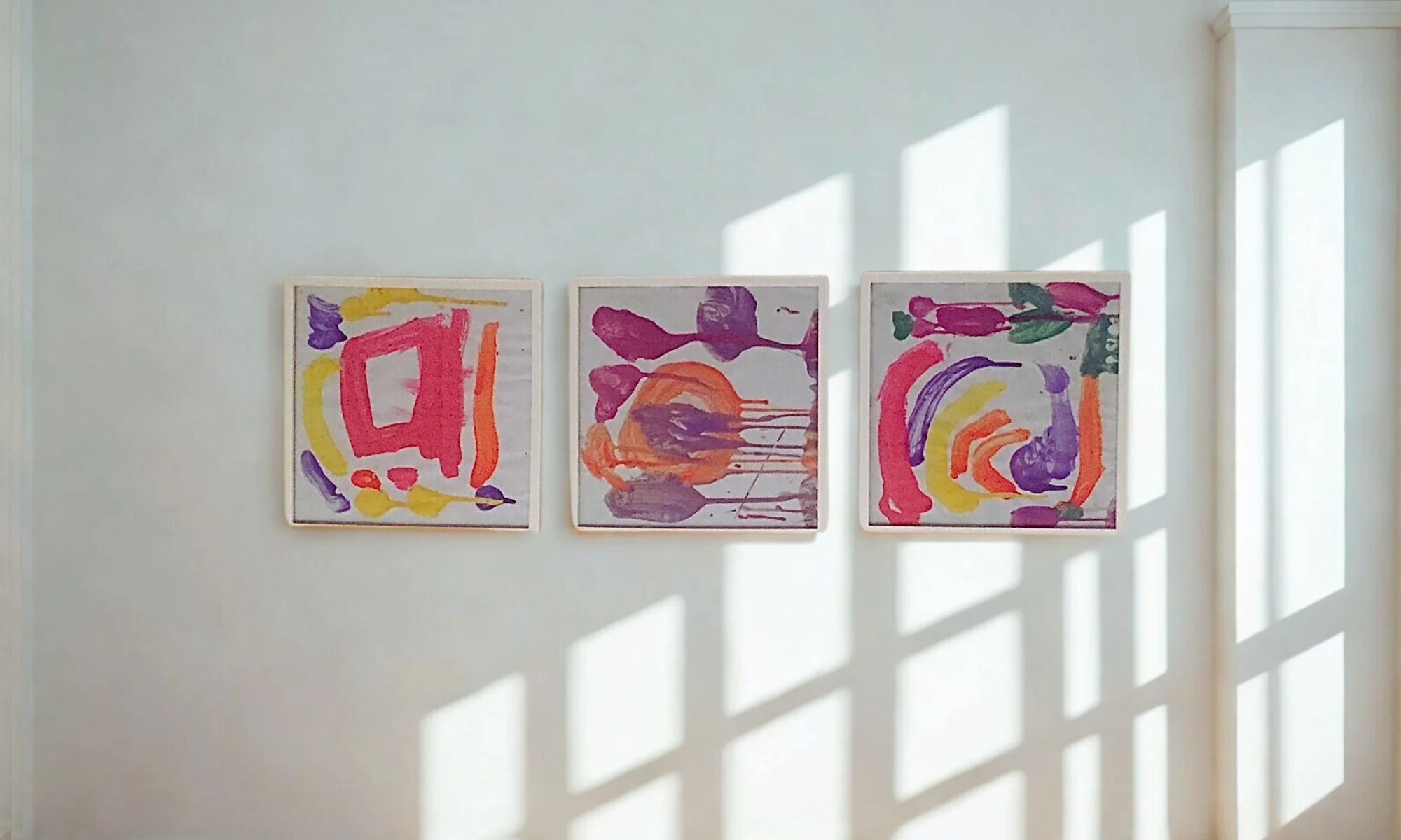 Three framed pieces of children's artwork displayed on a wall, representing joy pieces honored with care — Organizing with Presence, professional home organizer serving Philadelphia and NYC.