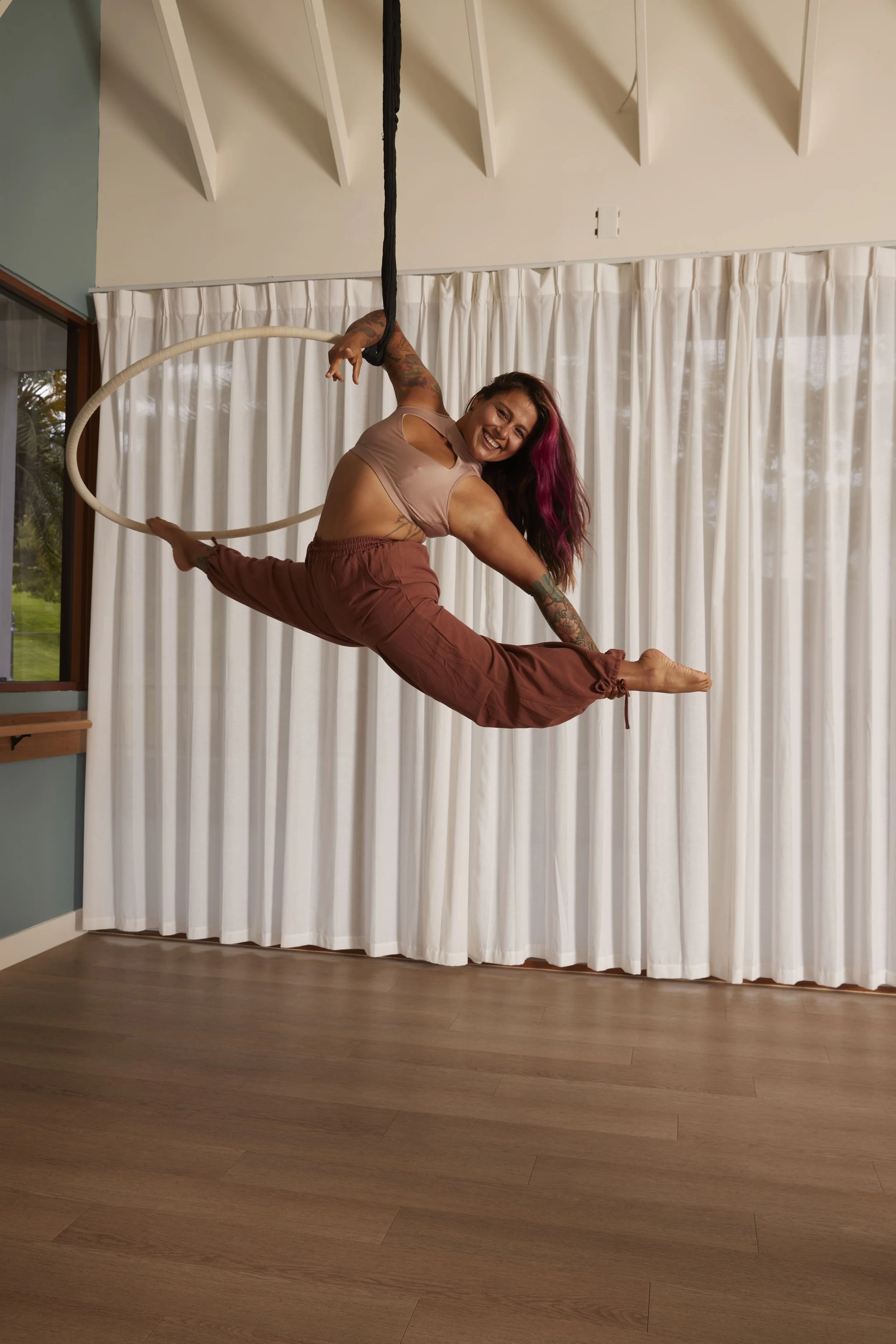 photo of aerialist hanging upside down in a hoop in a bright white room