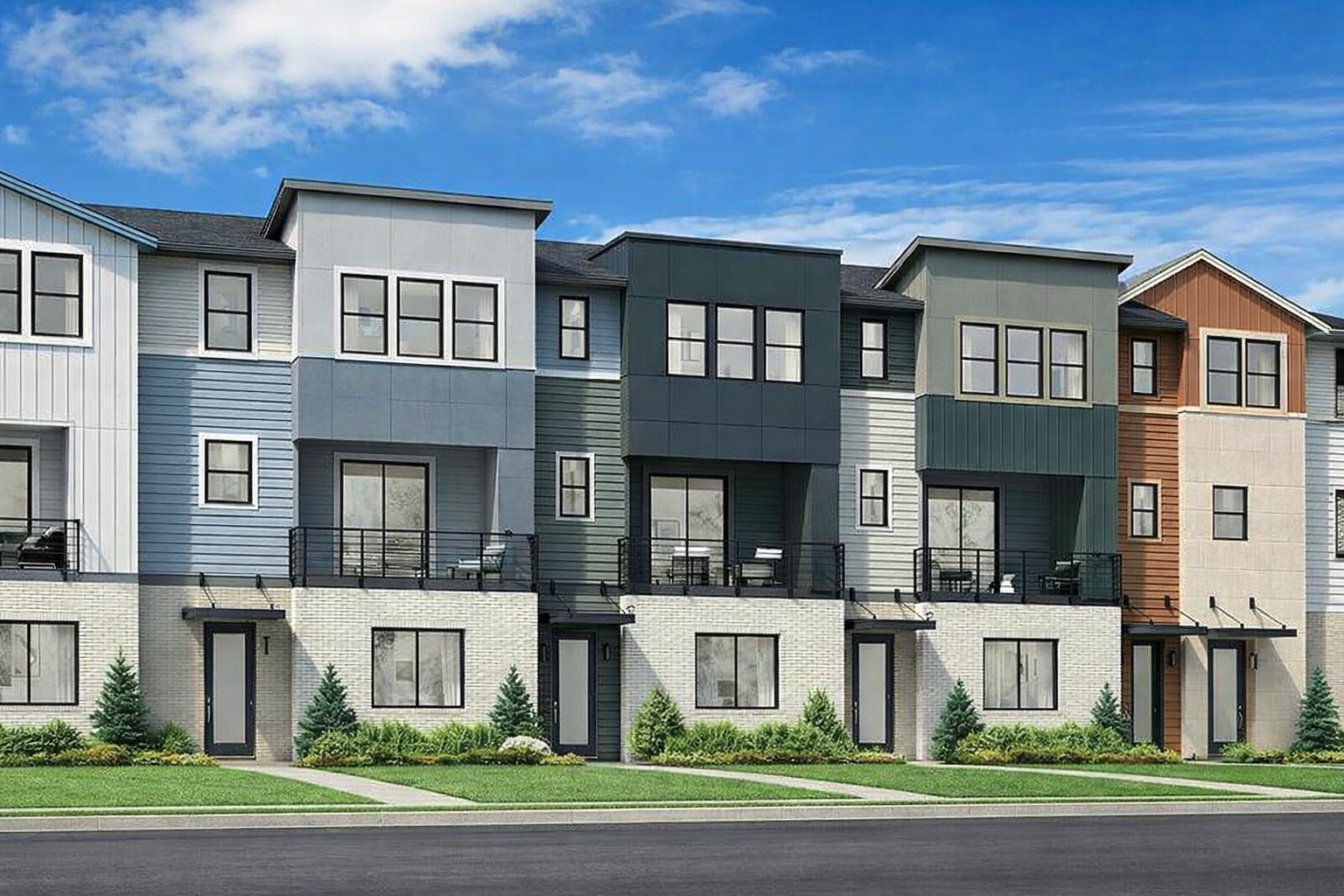 Modern kitchen with light wood cabinets, stainless steel appliances including a dishwasher, oven, and refrigerator, and a laundry area with a washing machine and dryer in the background. The room has wood-look flooring and white walls with small windows.