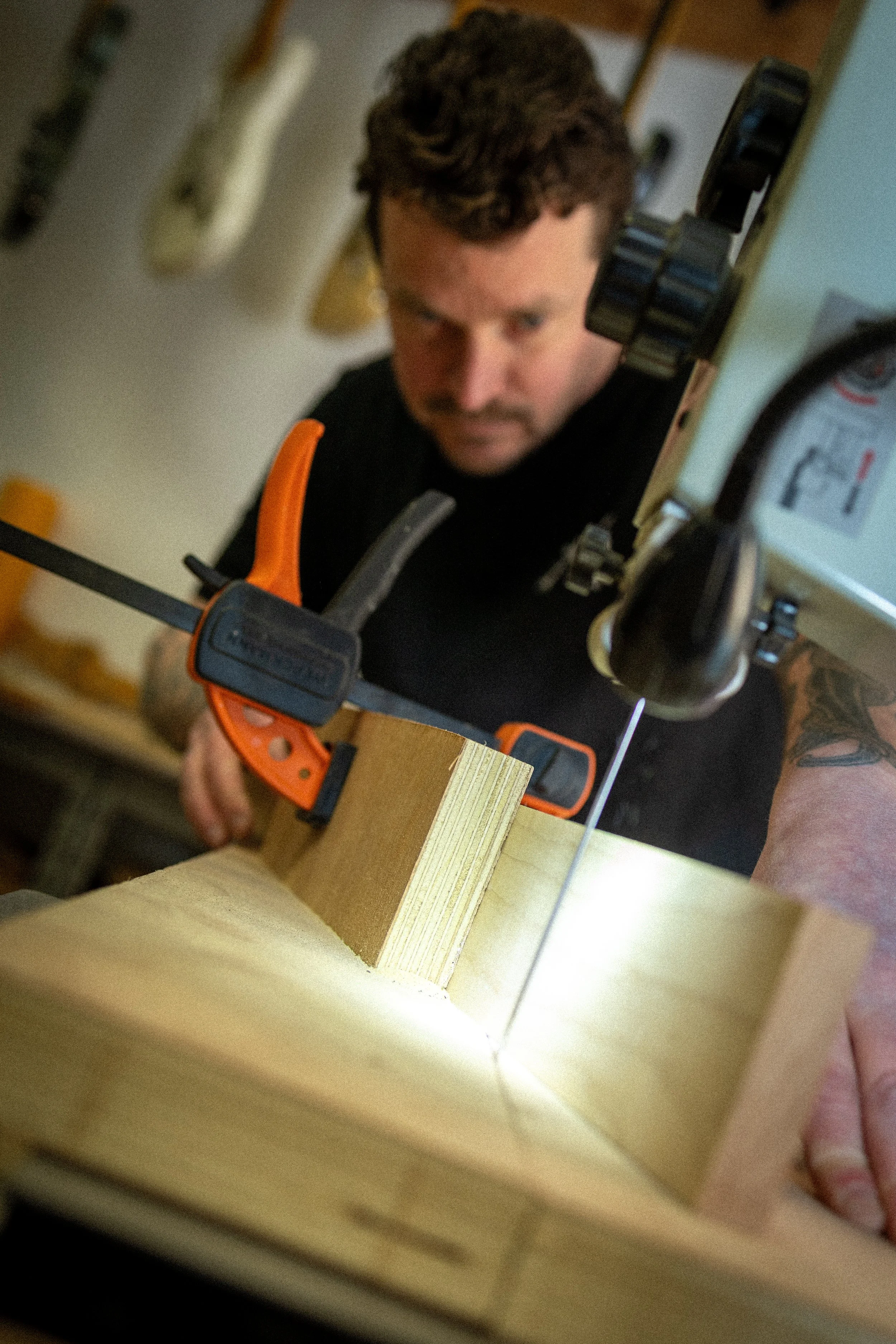 Een man die met een zaag een stuk hout doorgezaagt in een werkplaats.