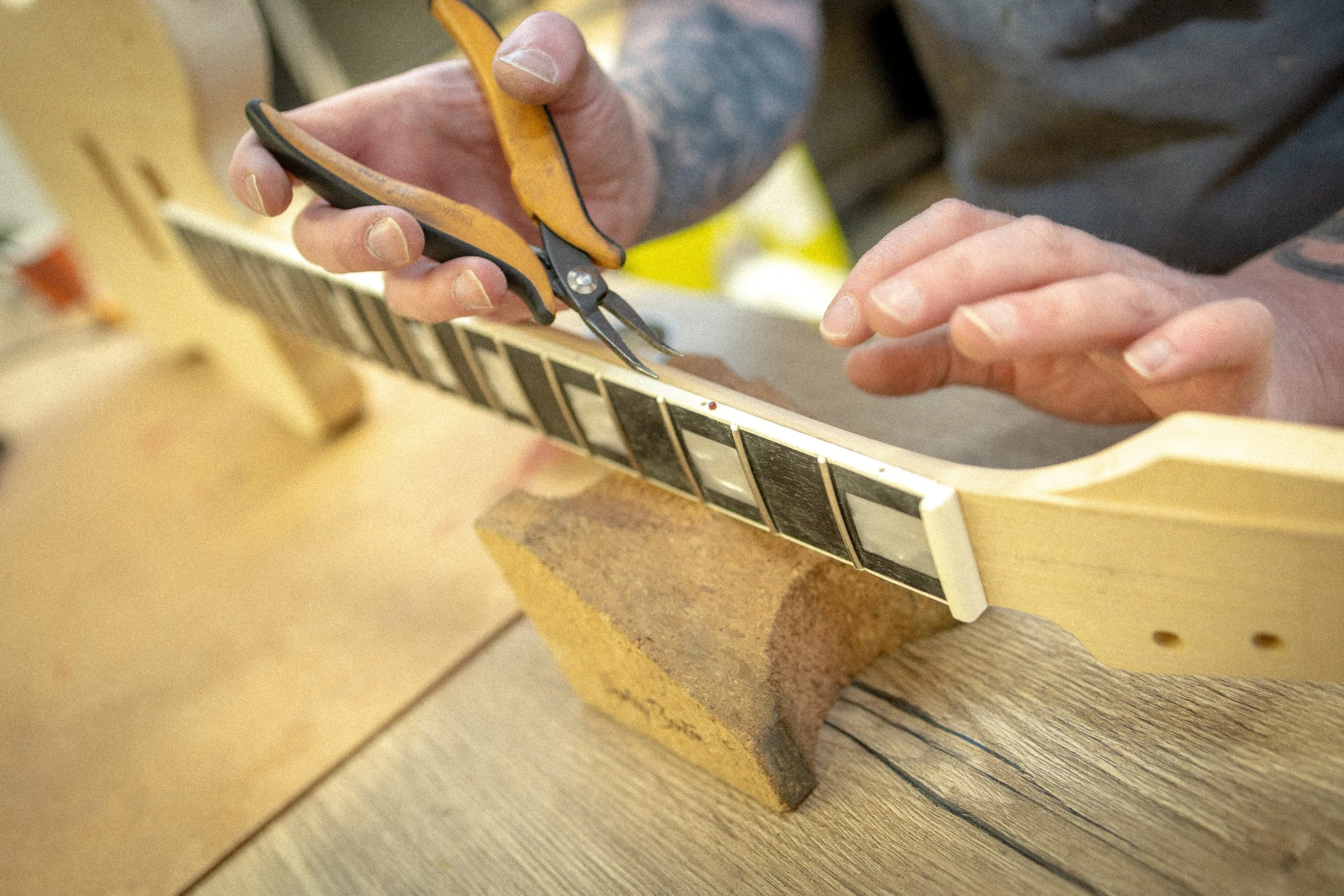 Persoon snijdt hout met een kleine takkenschaar in een werkplaats.