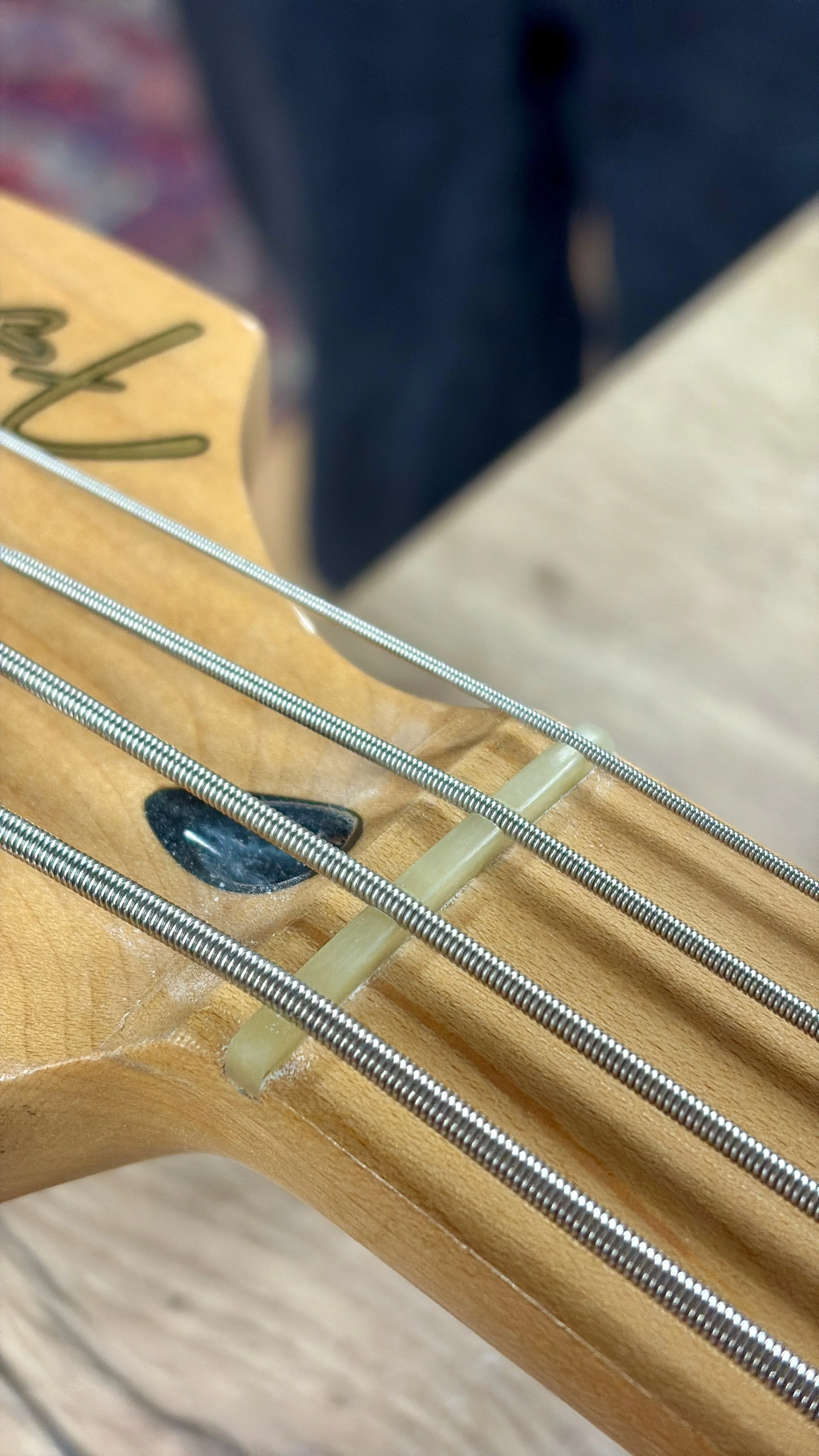 Close-up van de top van een akoestische gitaar, met zicht op de brug en de snaren.