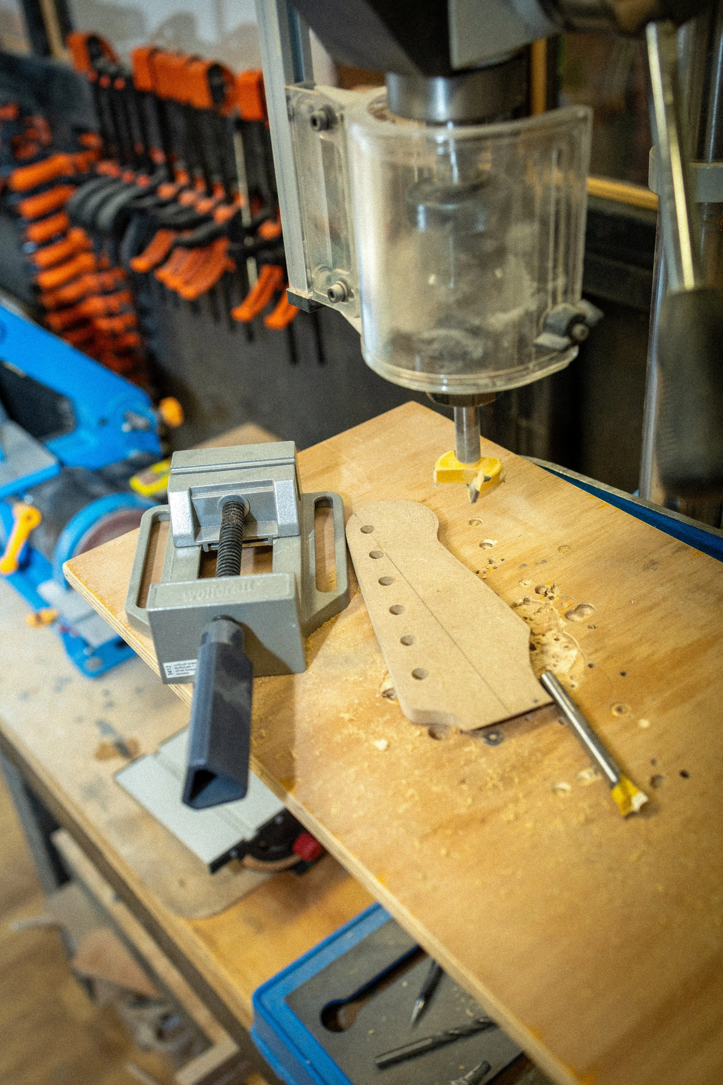 Een werkbank met een houtbewerking machine, houtelijven, schroevendraaier, klemmen en andere gereedschappen in een werkplaats.