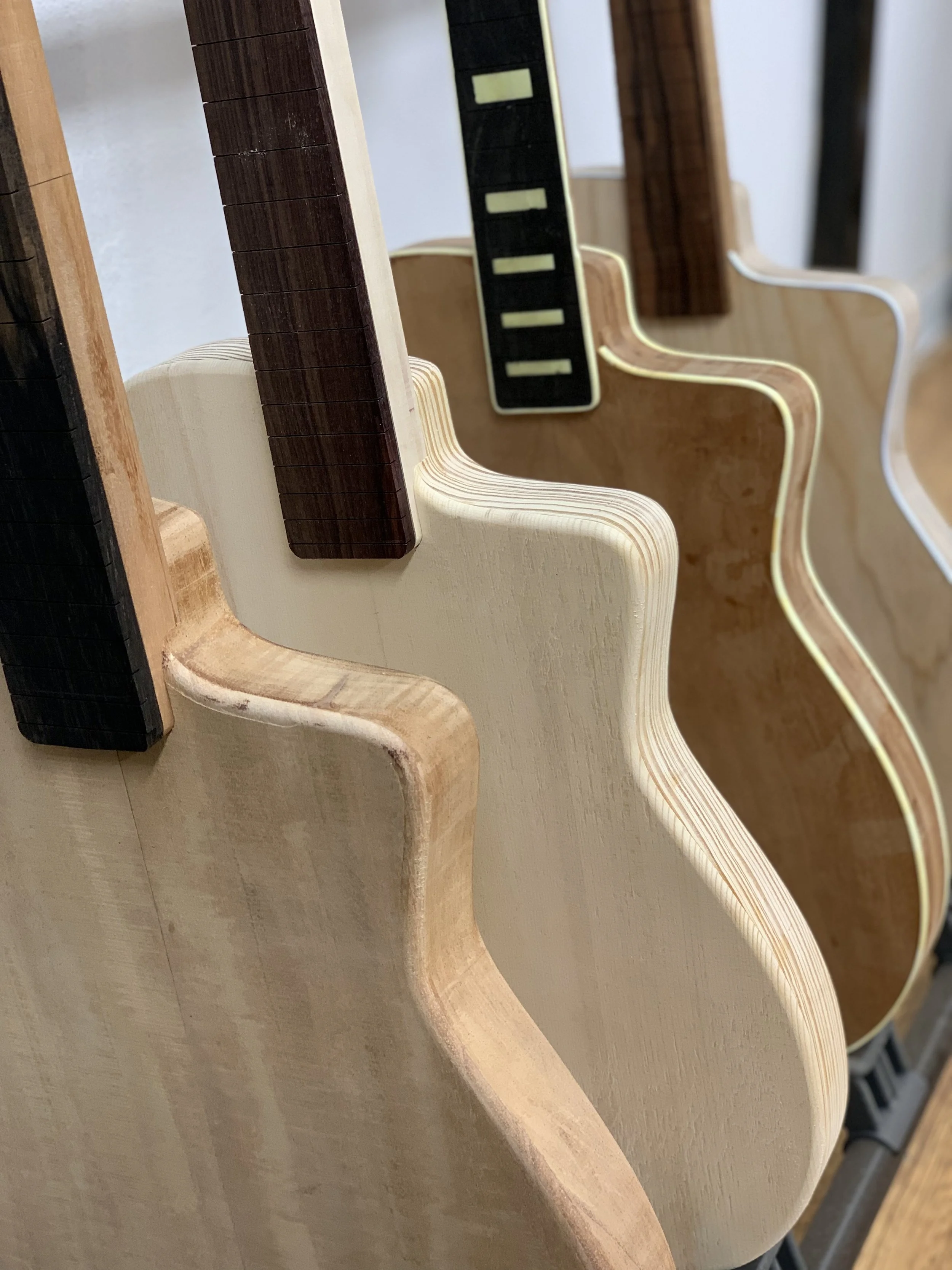 Meerdere houten en kunststof onderdelen voor meubel- of modelbouw, gekleurde en geschuurde oppervlakken, verspreid op een werkplek.