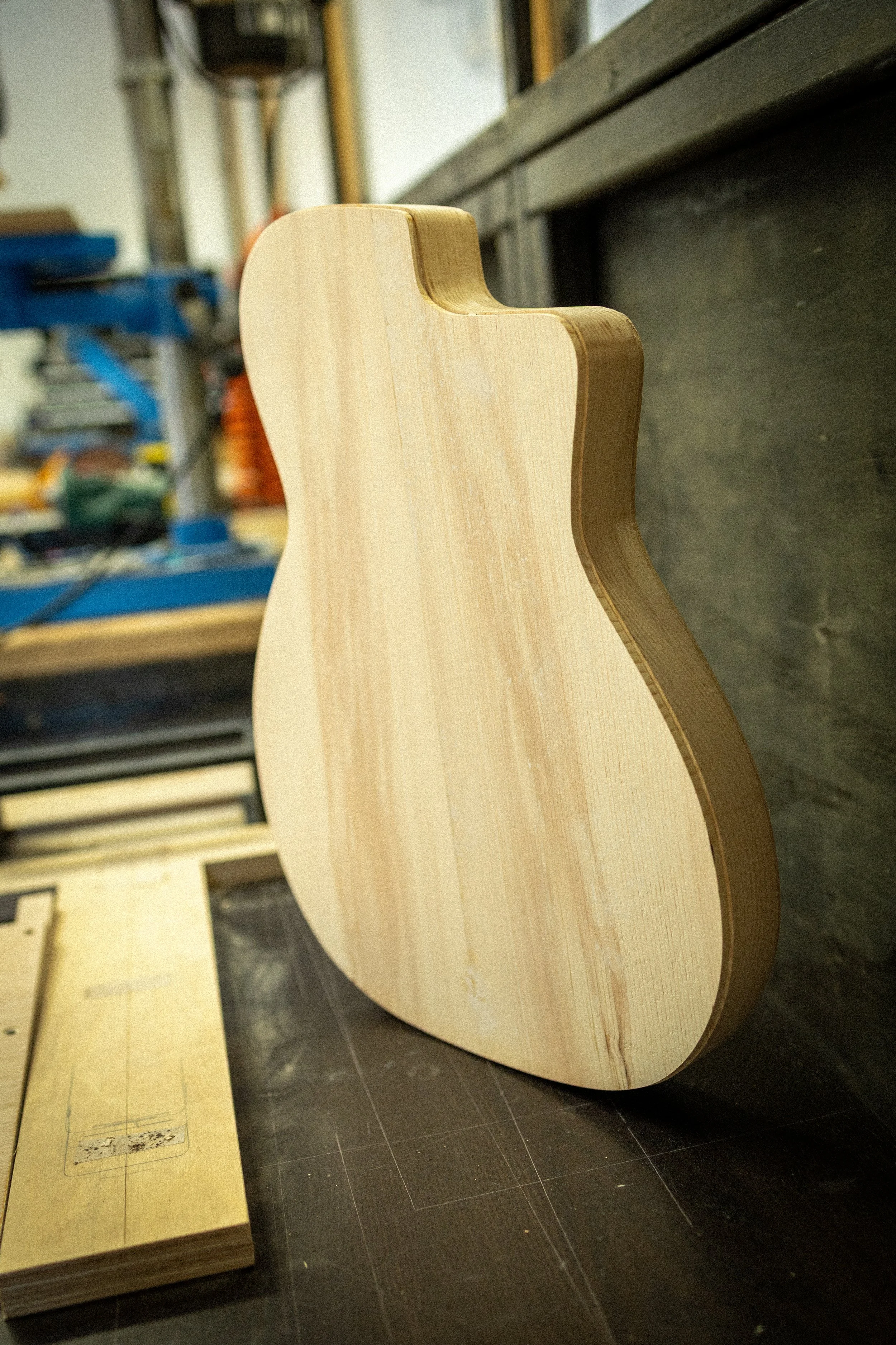 Onbewerkt houten meubelstuk in een werkplaats met enkele gereedschappen op de achtergrond.