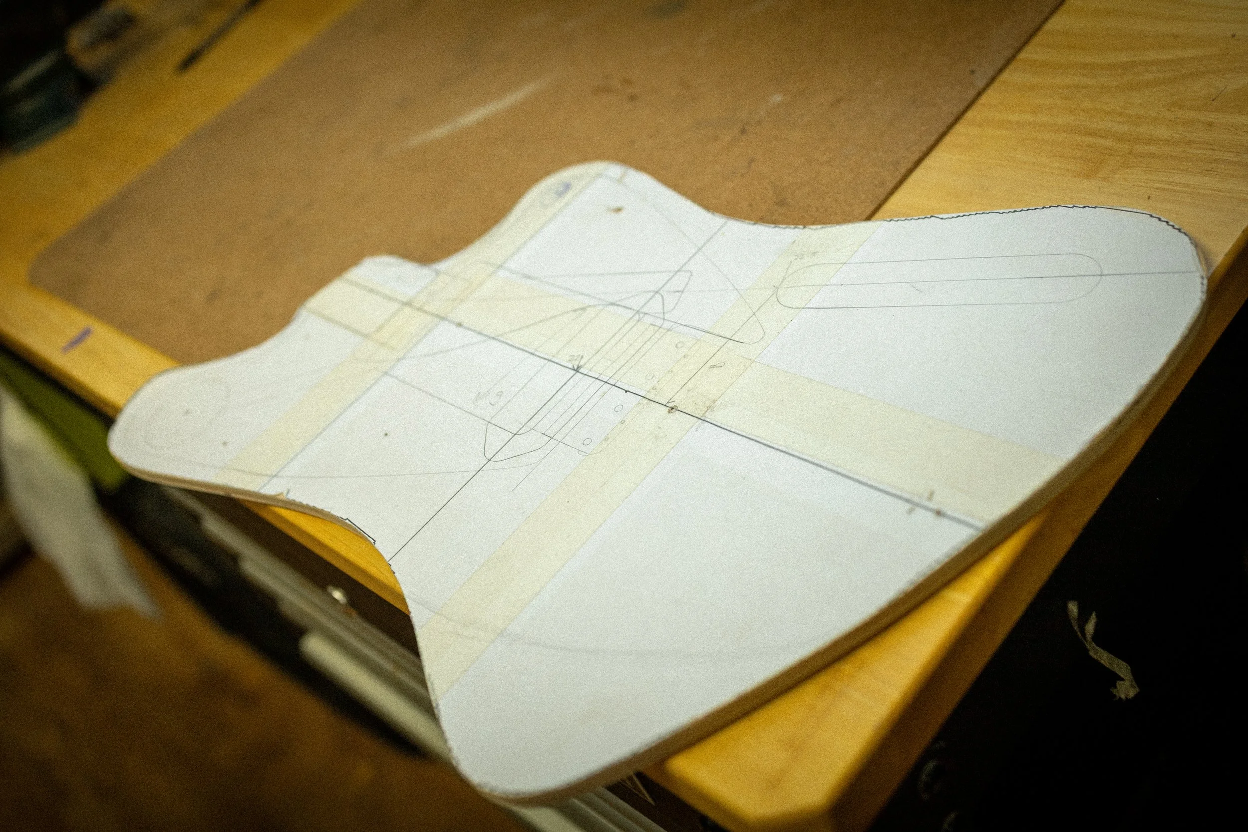 Een tekening of bouwplan op papier, bevestigd op een houten oppervlak met tape.