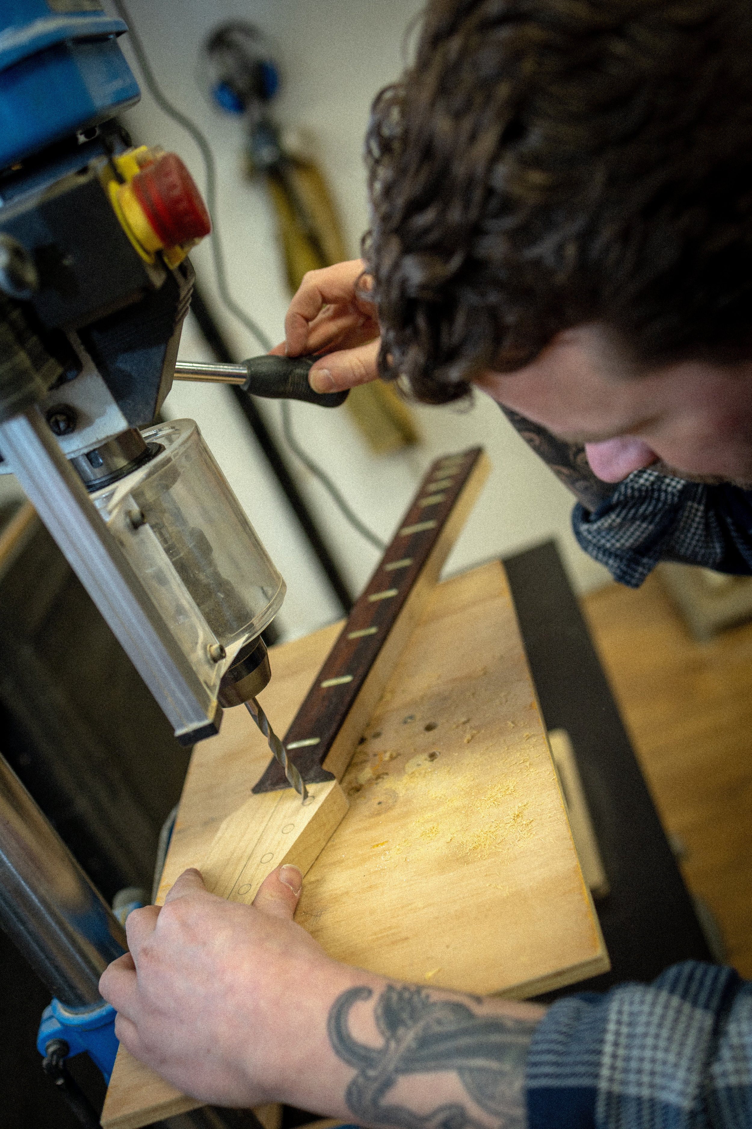 Persoon die een houten plank meet en markeert met potlood op een werkbank, omringd door gereedschap.