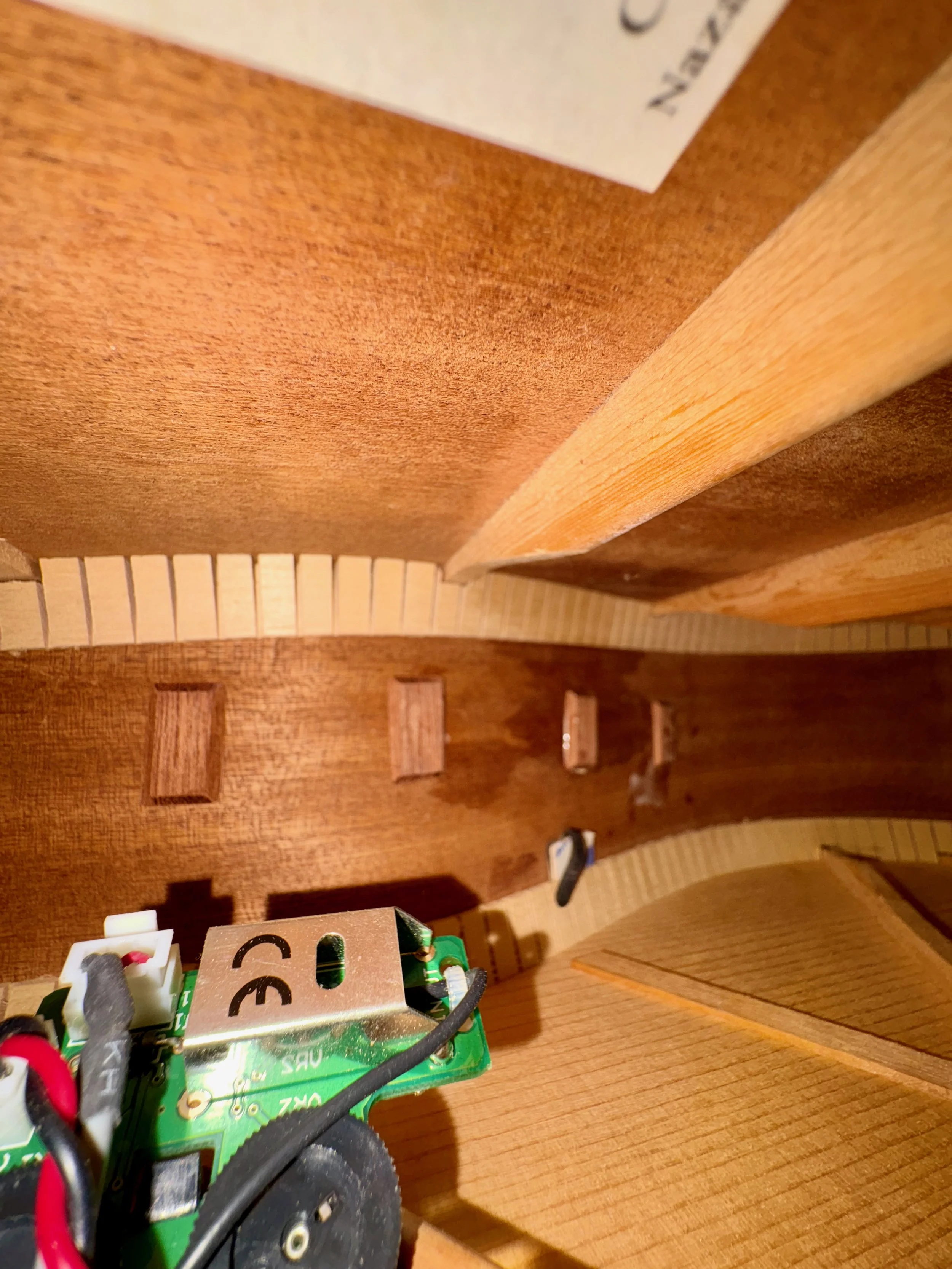 Close-up van een elektronische schakeling met draden en een breadboard op een houten oppervlak, met enkele houten blokken in de achtergrond.