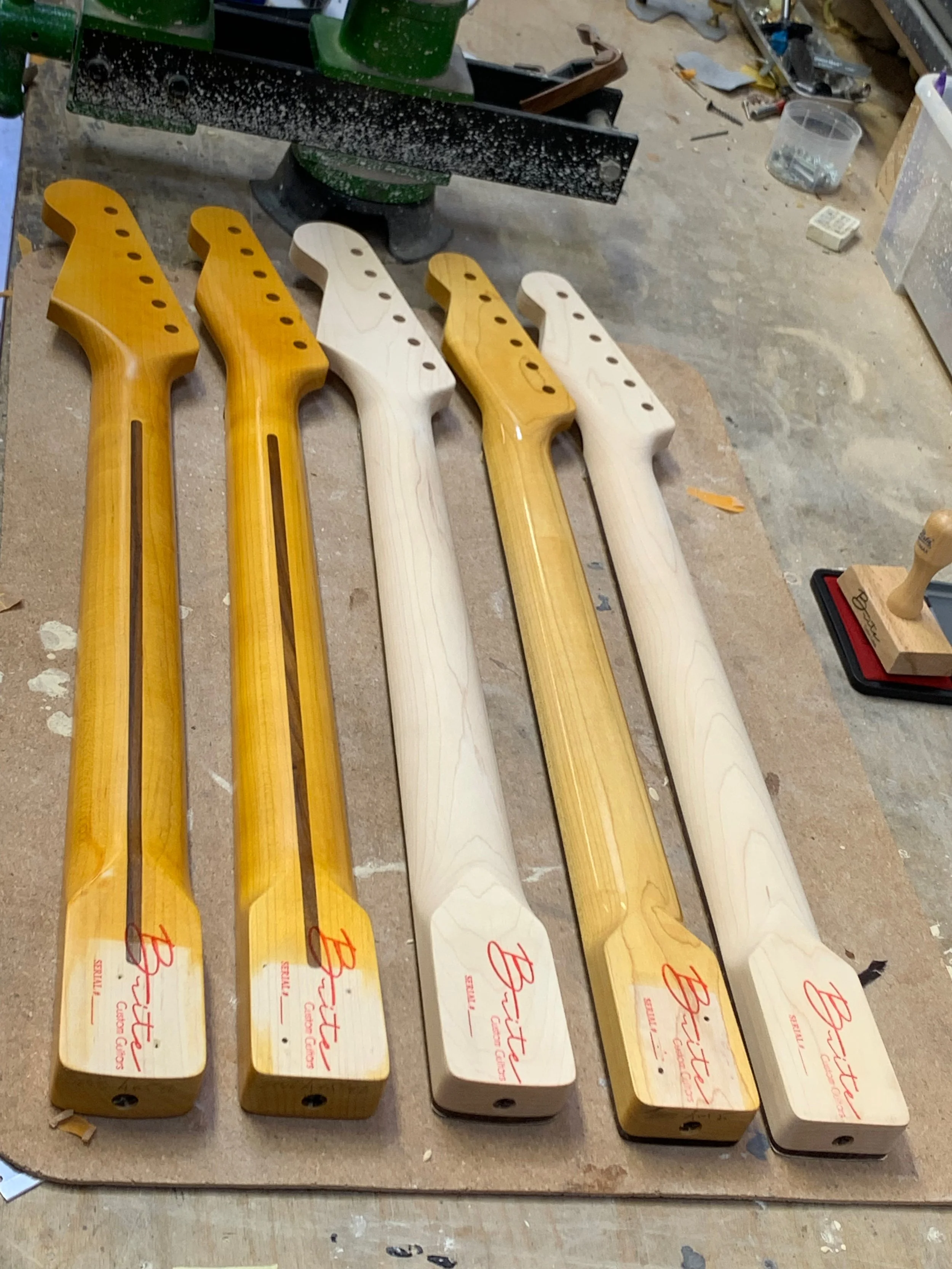 Vijftal houten koppen met de naam 'Bittner', gereed voor montage, op een werkbank in een werkplaats.