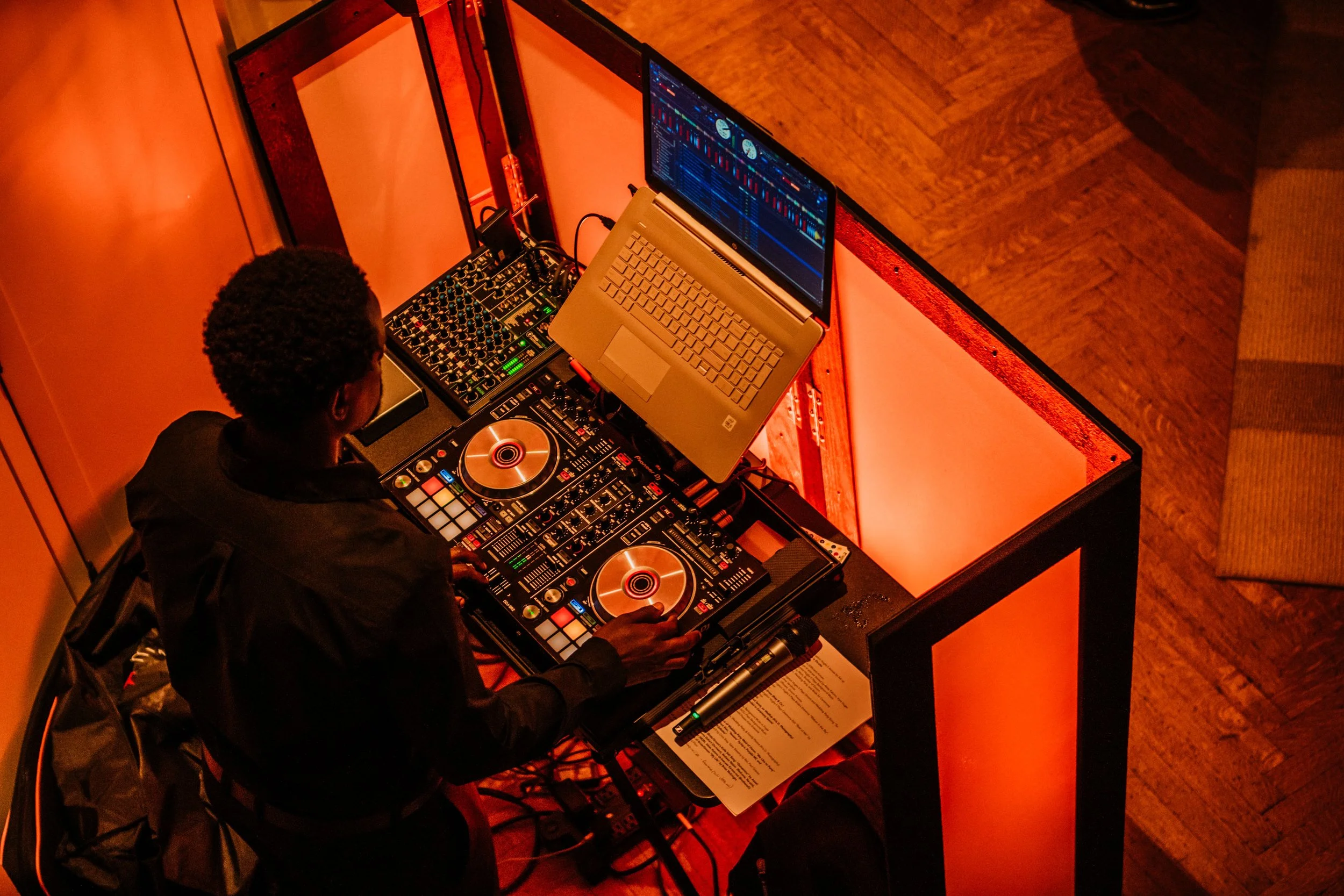 A DJ performing at a wedding, using mixing equipment and a laptop, viewed from above.