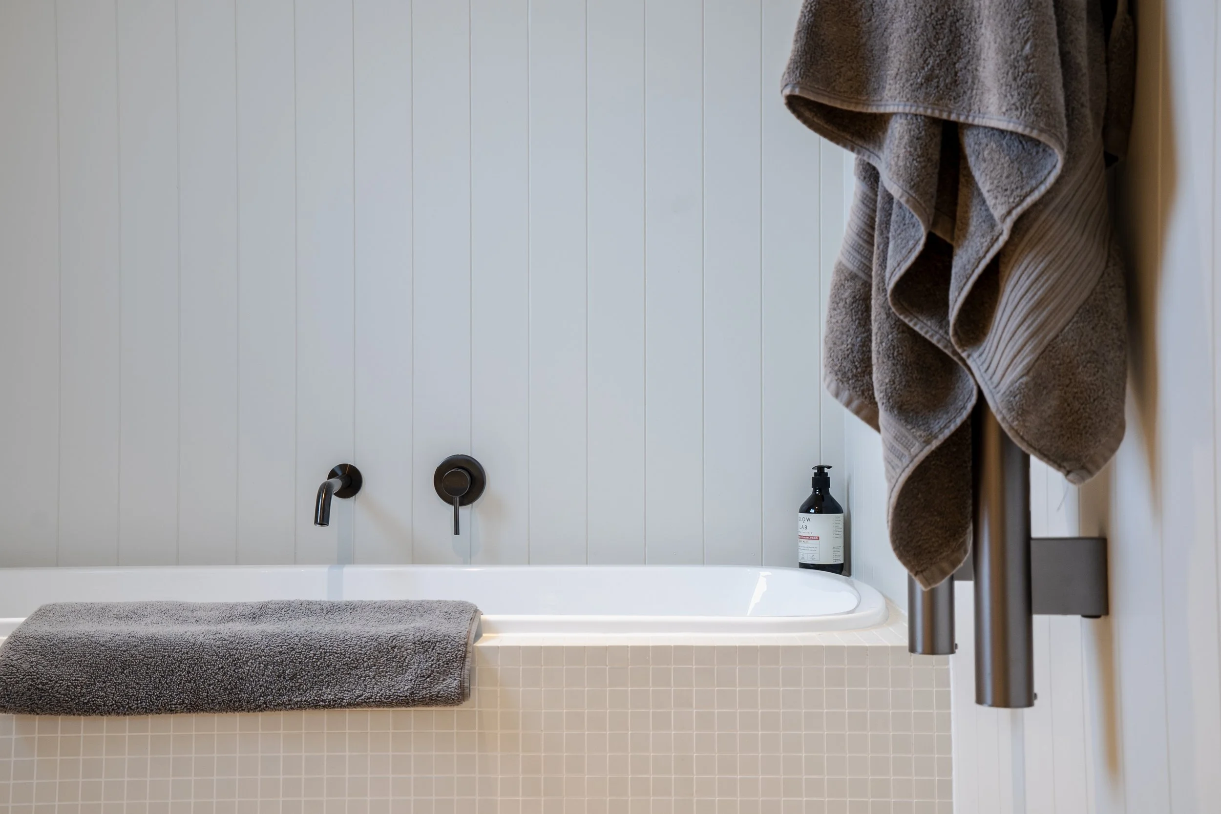 Modern Airbnb bathroom in Queenstown with grey towels, matte black tapware, and premium toiletries