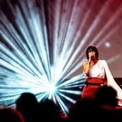 Kosheen’s Sian Evans delivering “Hide U” at a live electronic set with dramatic lighting.
