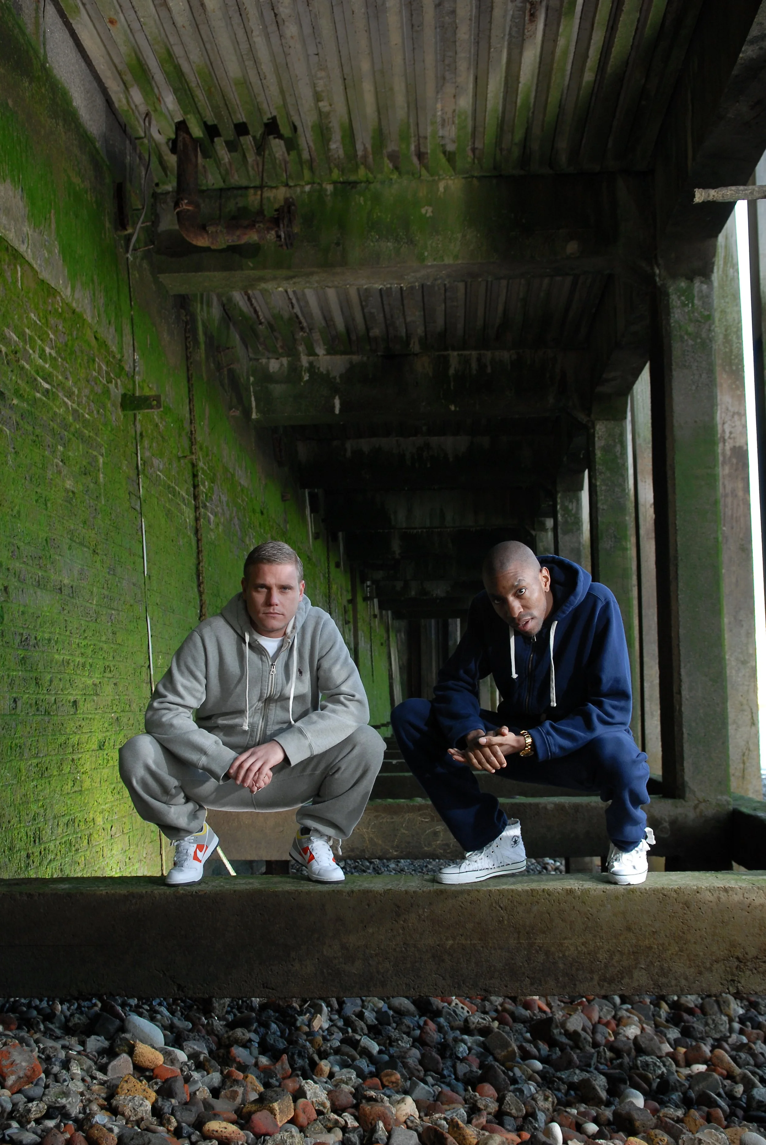 Artful Dodger duo during a stylish promotional photo shoot, iconic UK garage producers behind hits like “Re-Rewind” featuring Craig David, pioneers of 90s and 2000s dance music.