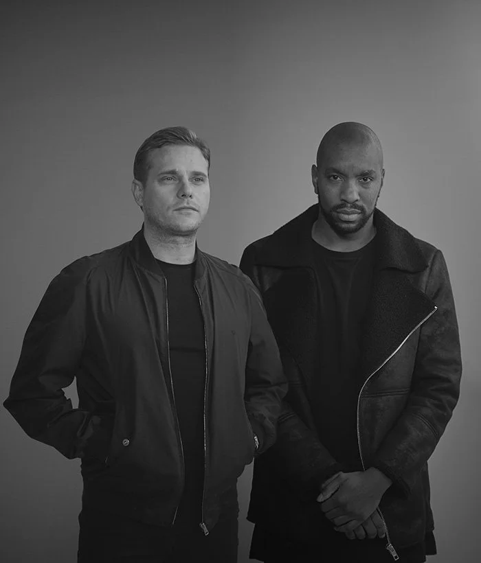 Artful Dodger duo during a stylish promotional photo shoot, iconic UK garage producers behind hits like “Re-Rewind” featuring Craig David, pioneers of 90s and 2000s dance music.