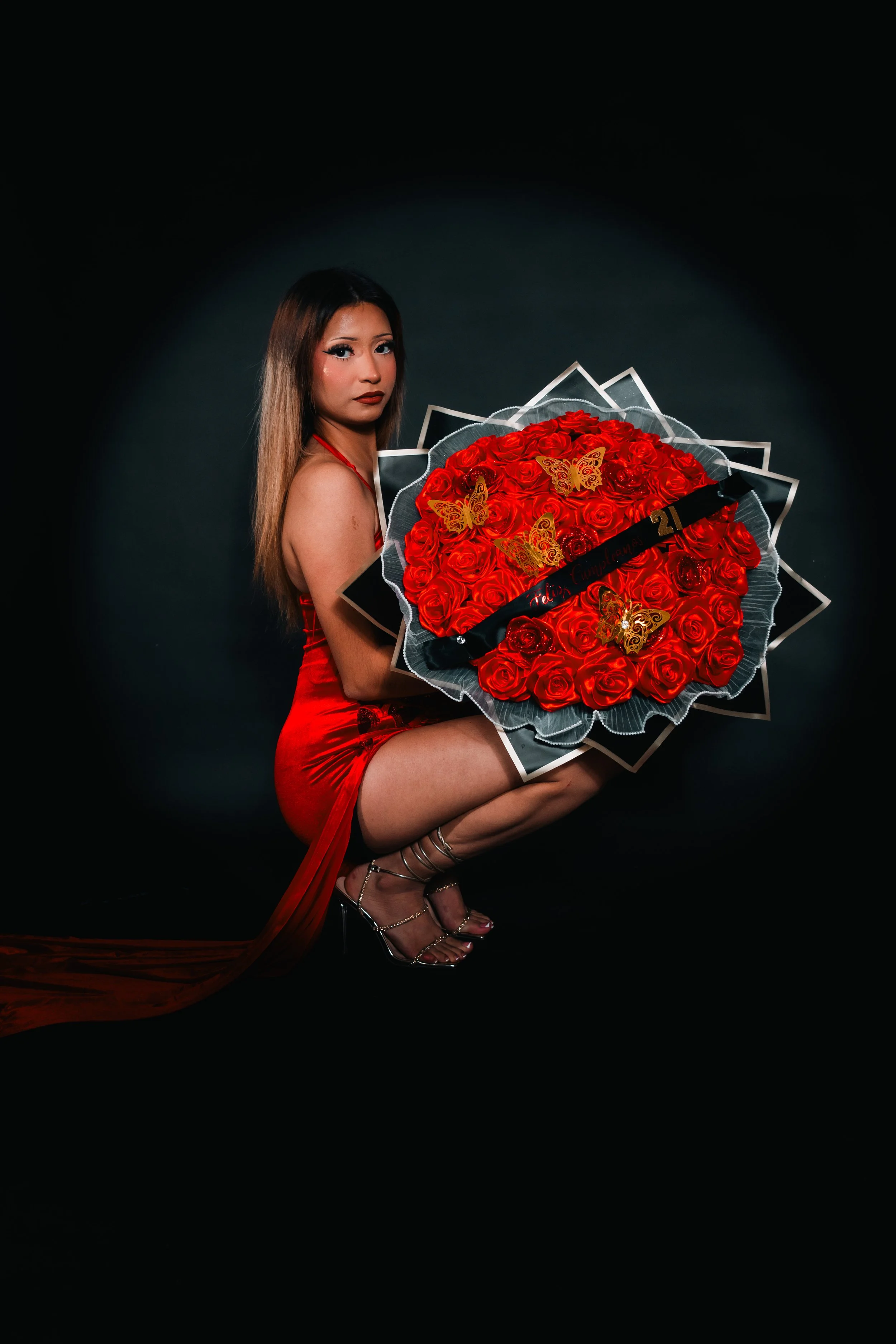 A girl in a red dress holding red roses for her 21st birthday photography session in Houston