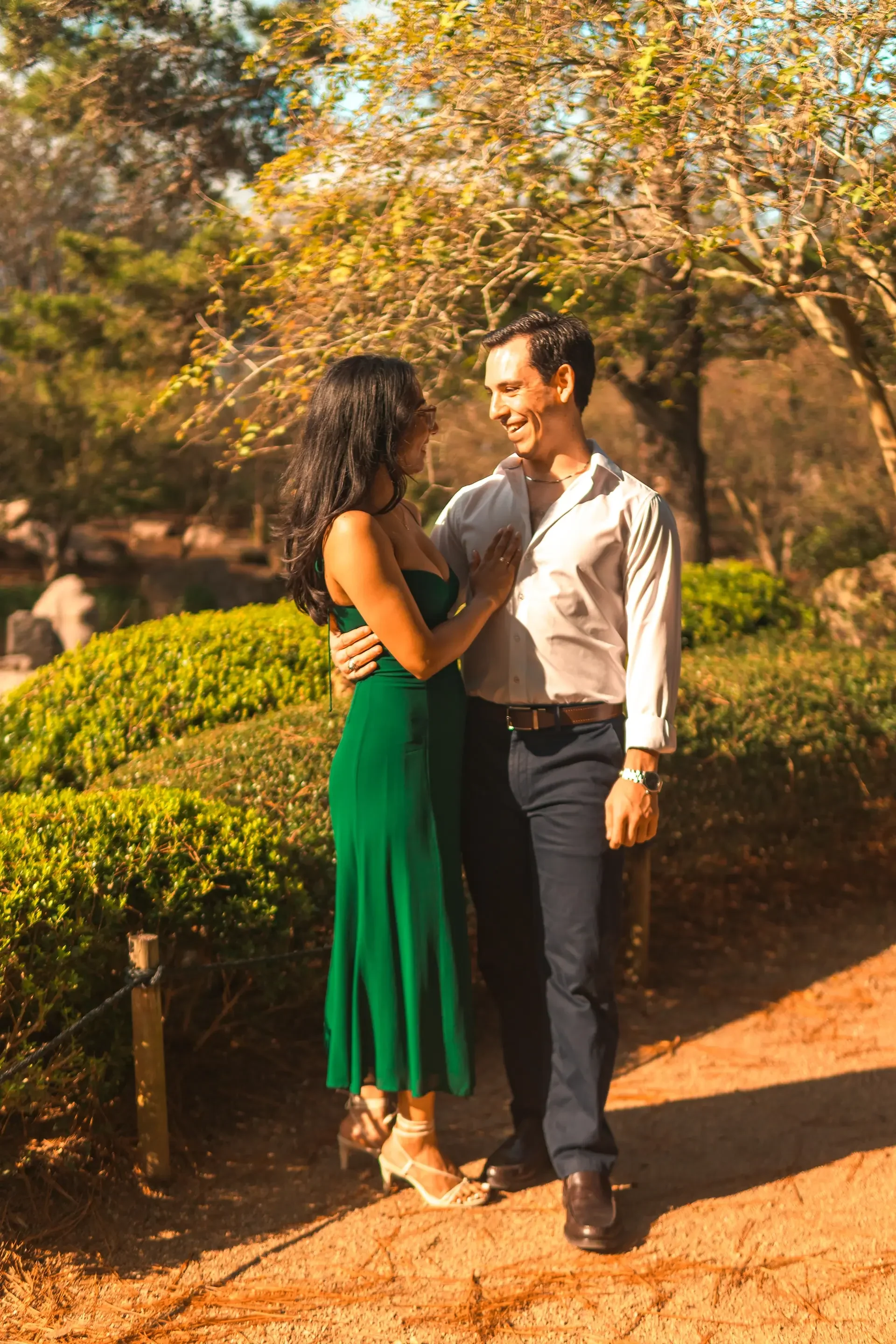 A couple smiling towards each other as an engagement photographer captures their perfect moment.