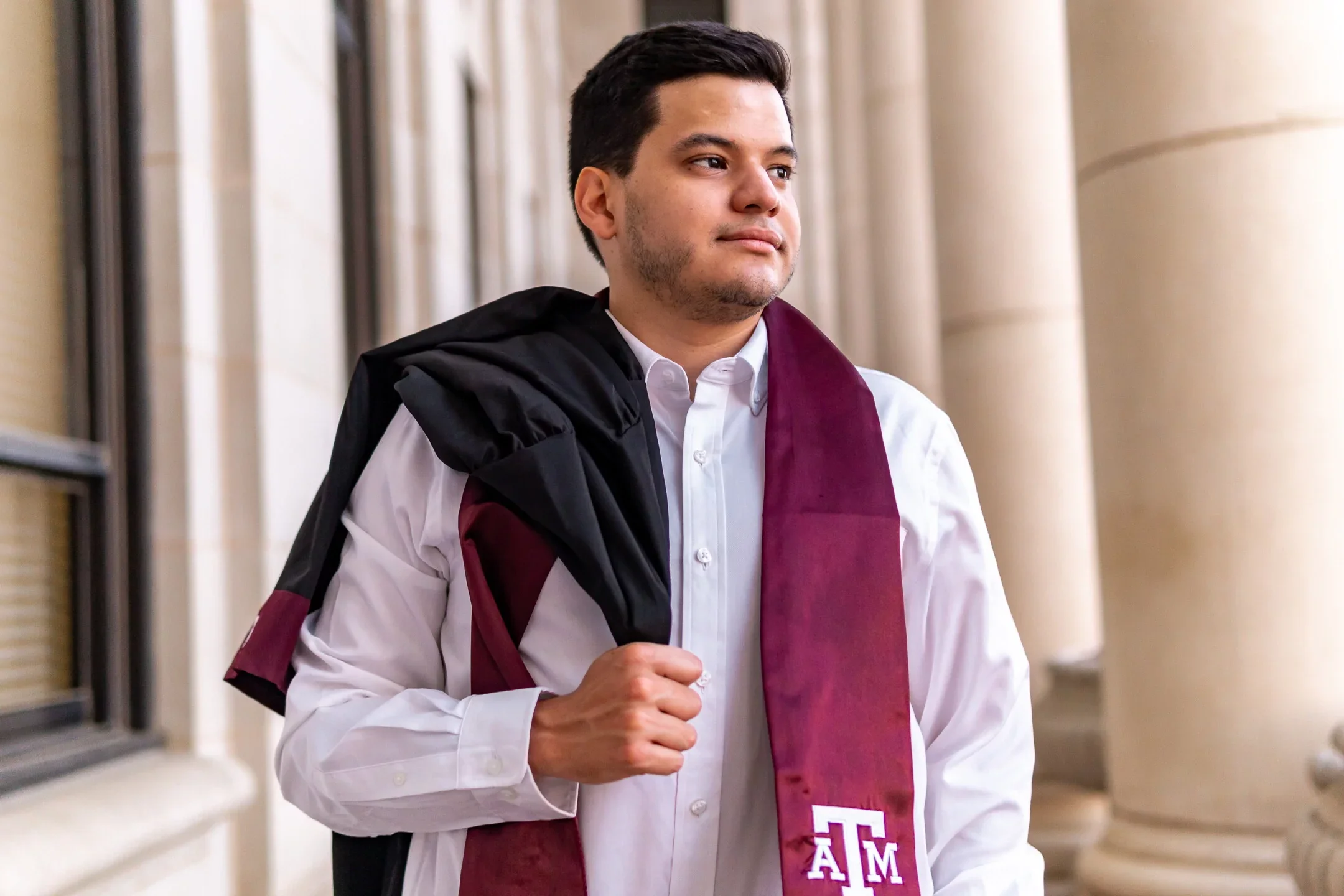 A recent college graduate is getting his headshot taken by a graduation photographer.