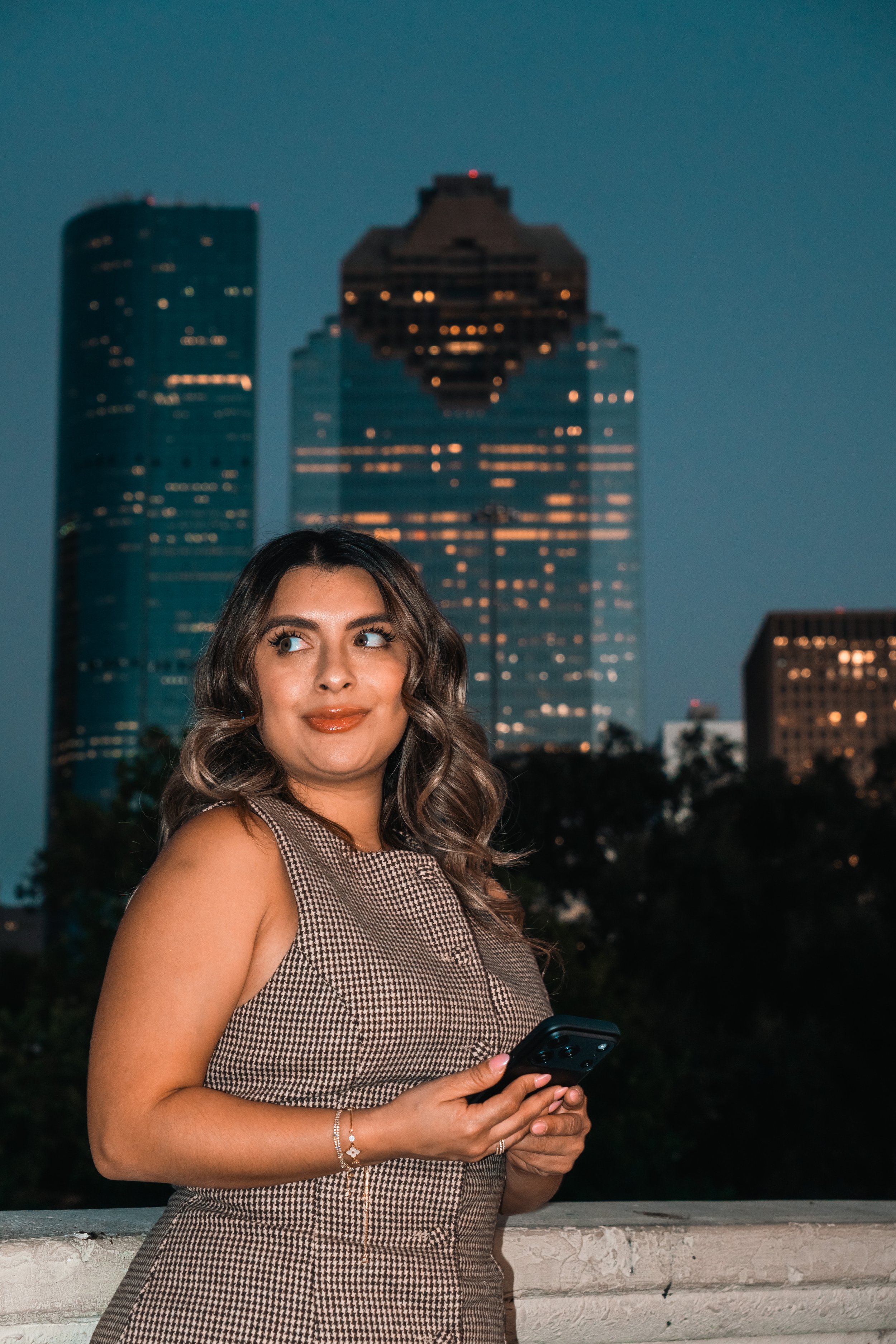 A girl holding a phone with Houston on the background during her Birthday Photography Session