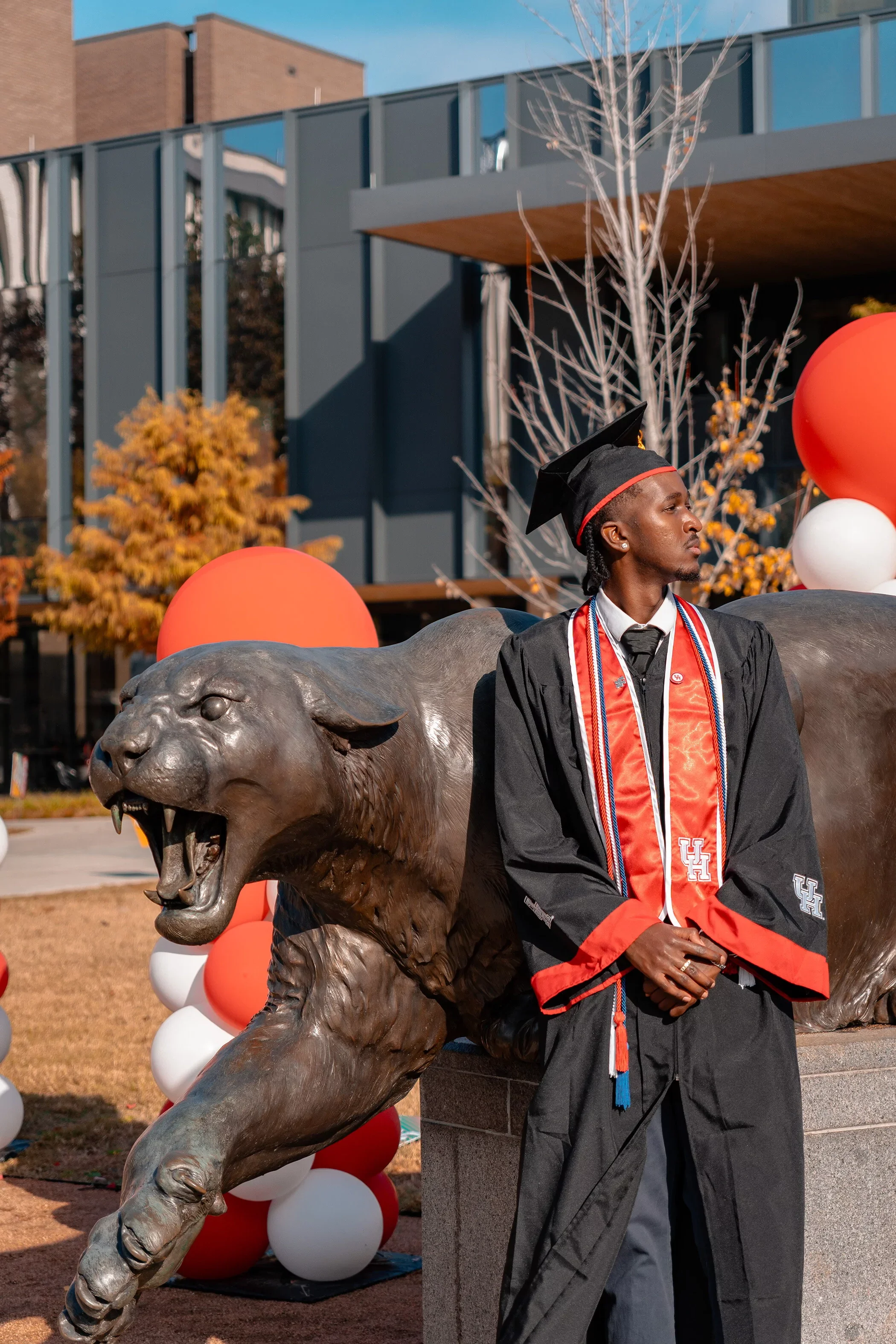 A young UH student getting his cap and gown photo taken by a graduation photographer in Houston.