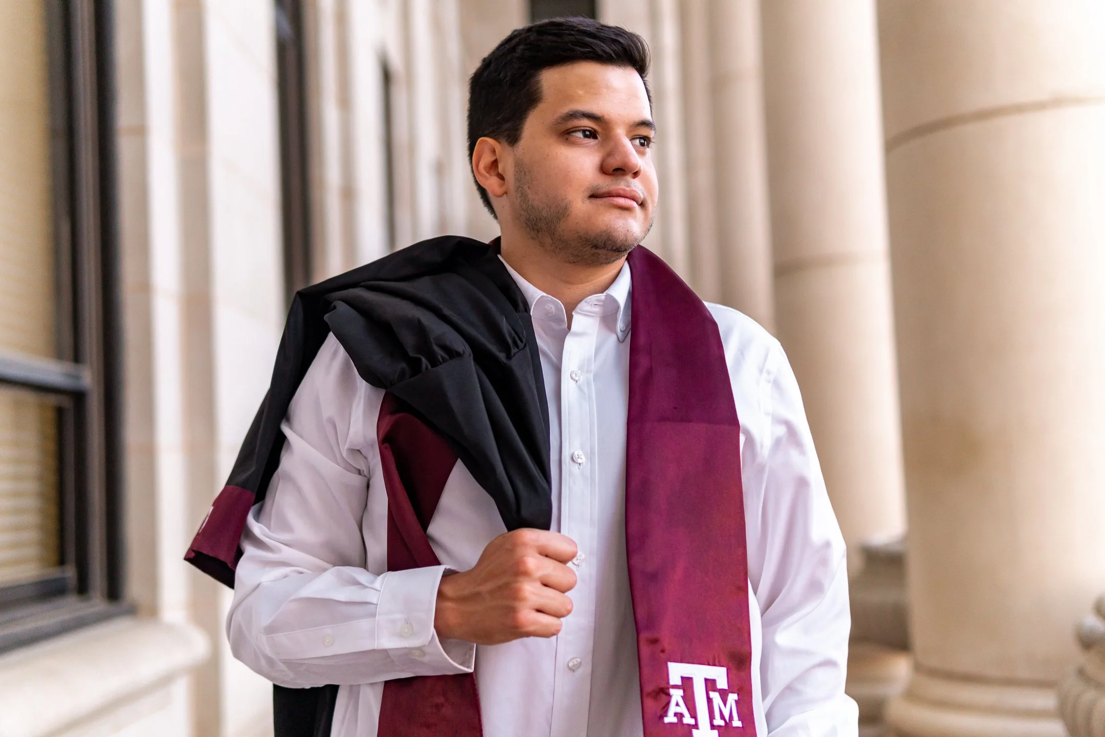 A recent college graduate is getting his headshot taken by a graduation photographer.