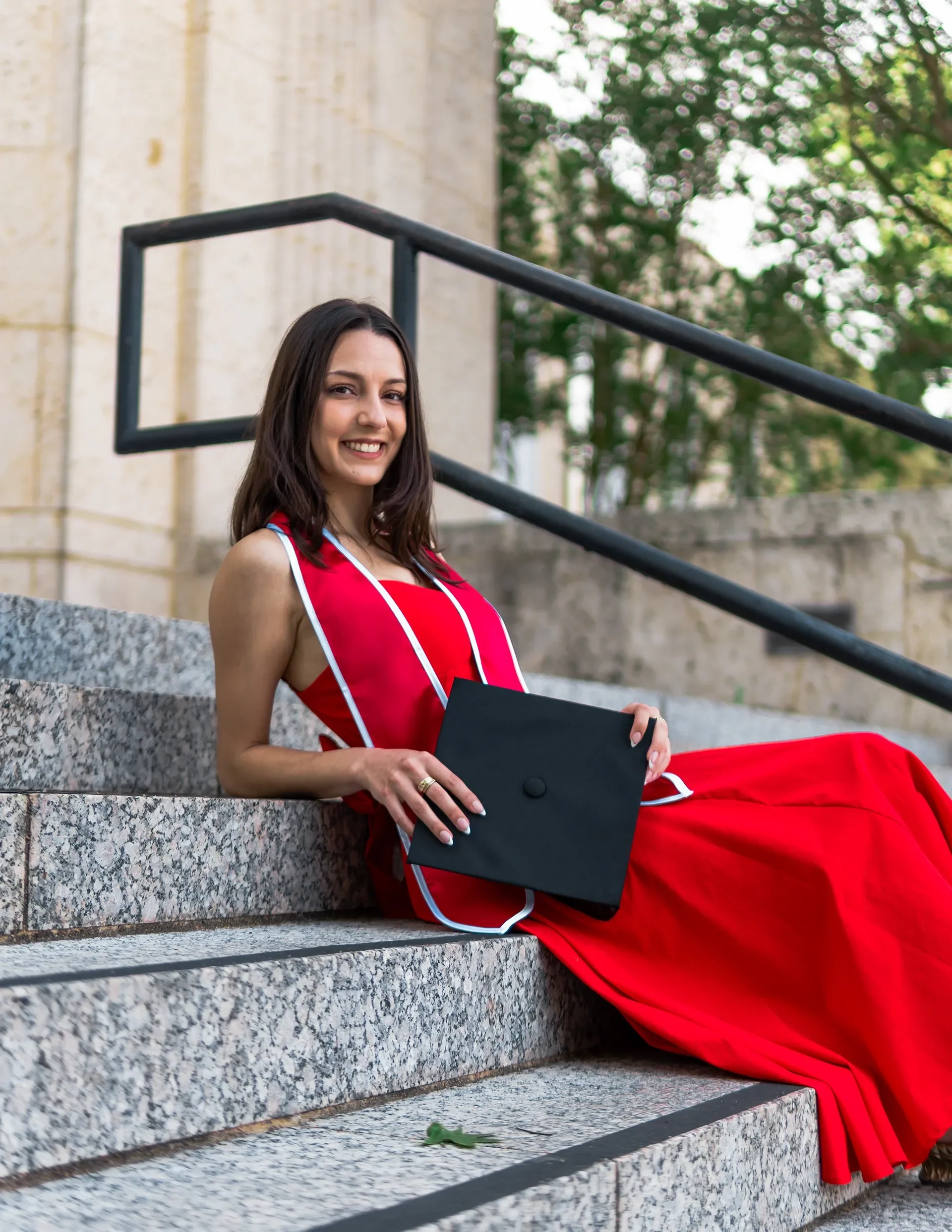 A UH Student posing for a Graduation Photographer next to the Cullen Building in the University of Houston.