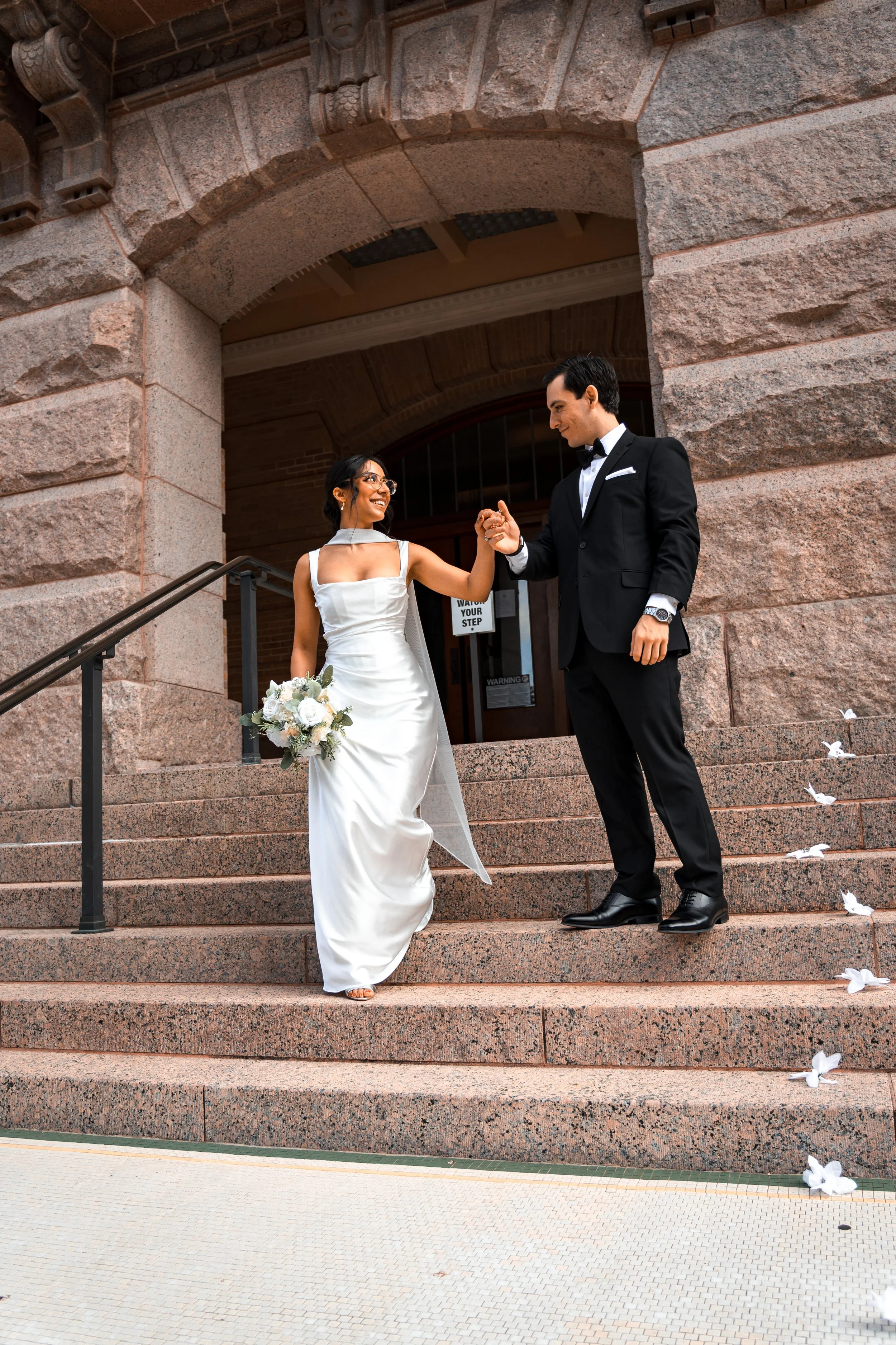 An engaged couple dressed up walking down stairs to be captured by an engagement photographer.