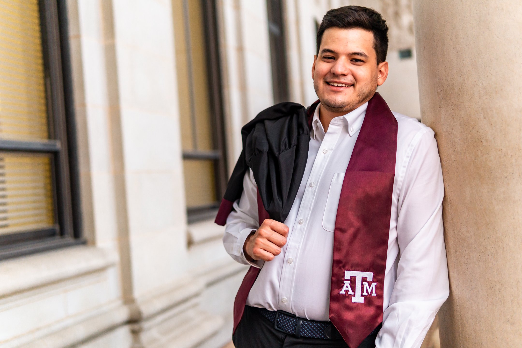 A recent A&M graduate having his photo taken by a graduation photographer from Houston.