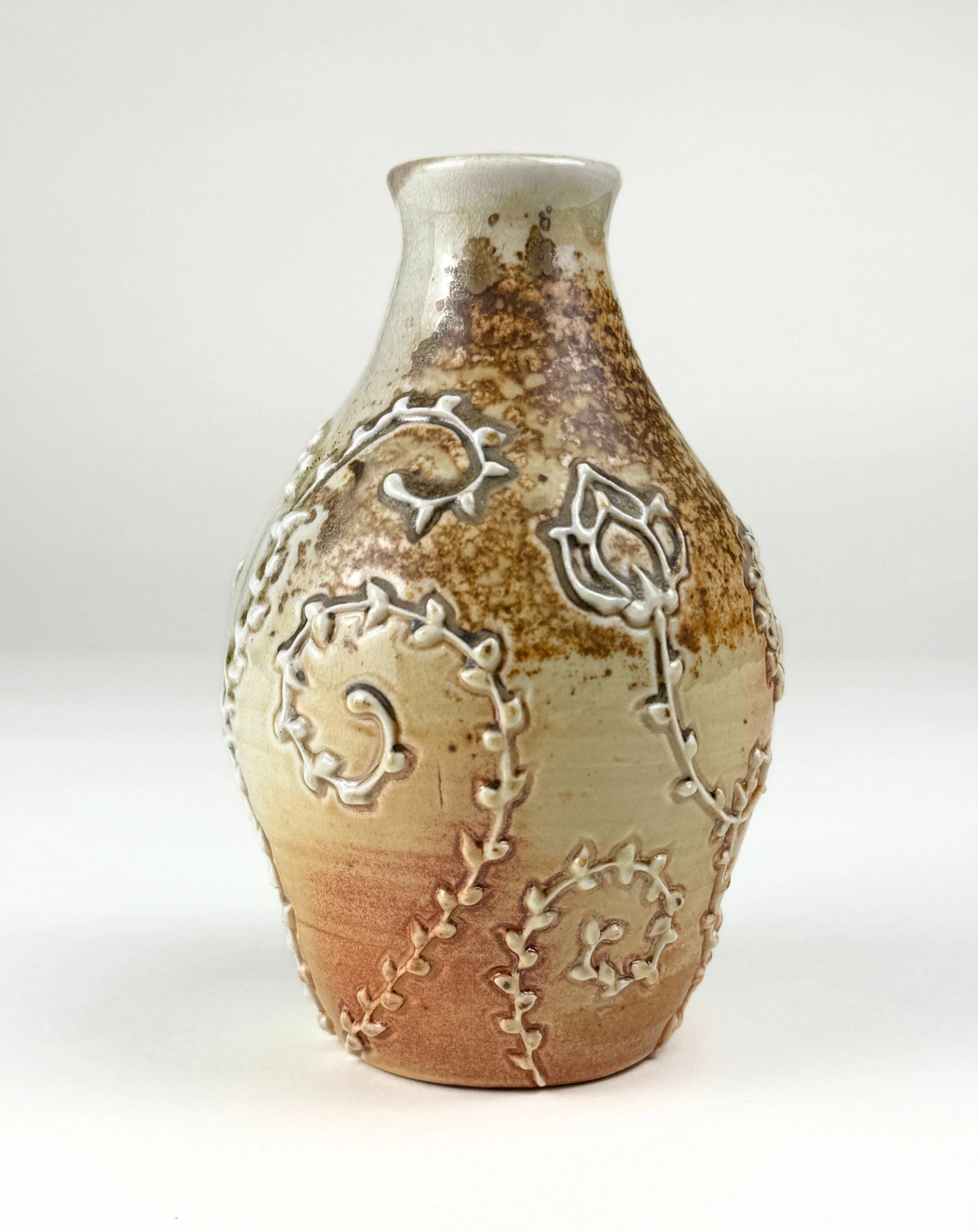 Decorative ceramic vase with embossed floral and vine patterns, glazed in earthy tones of beige, brown, and cream.