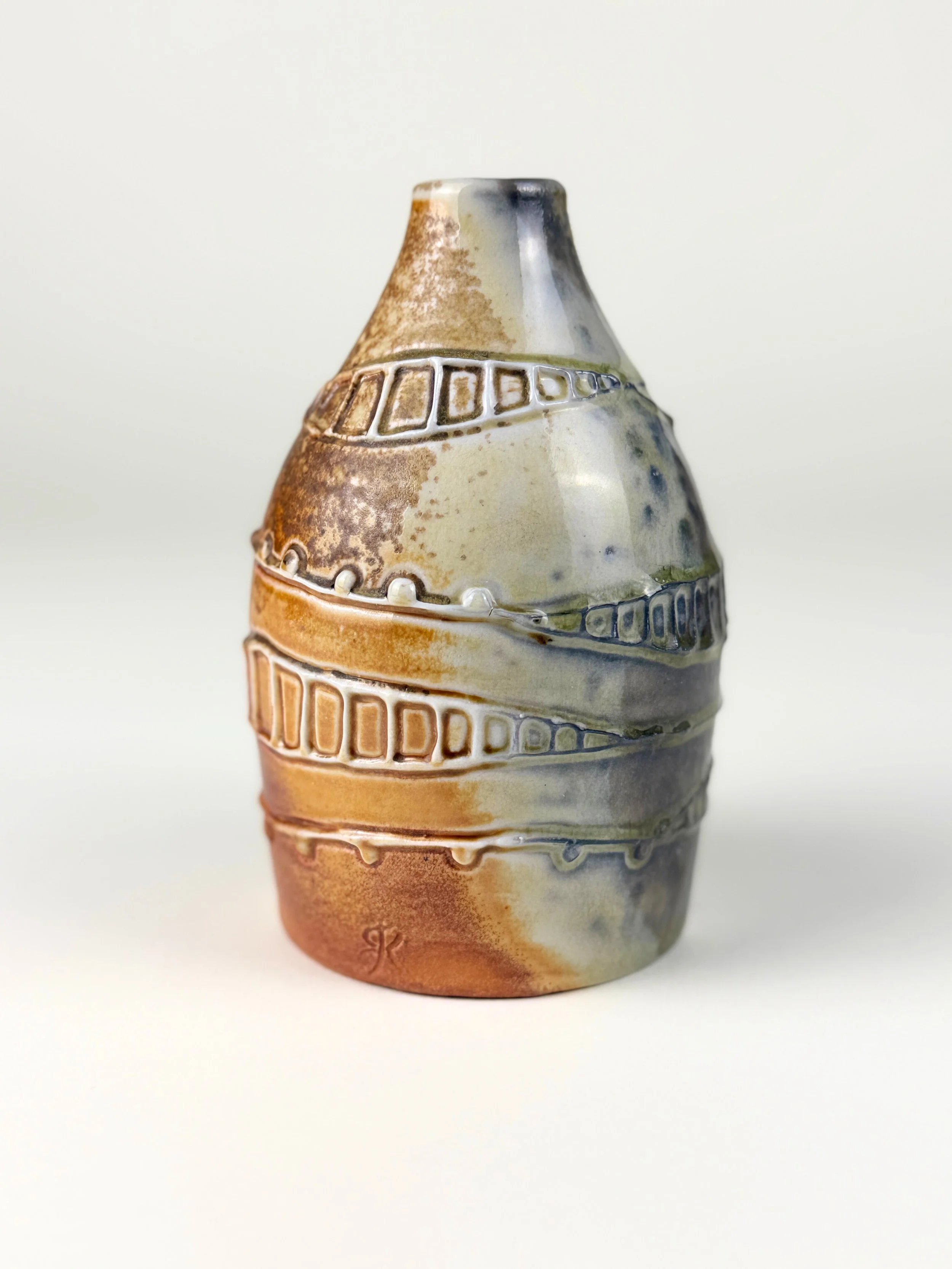 Ceramic vase with earthy tones and textured geometric patterns, set against a plain white background.
