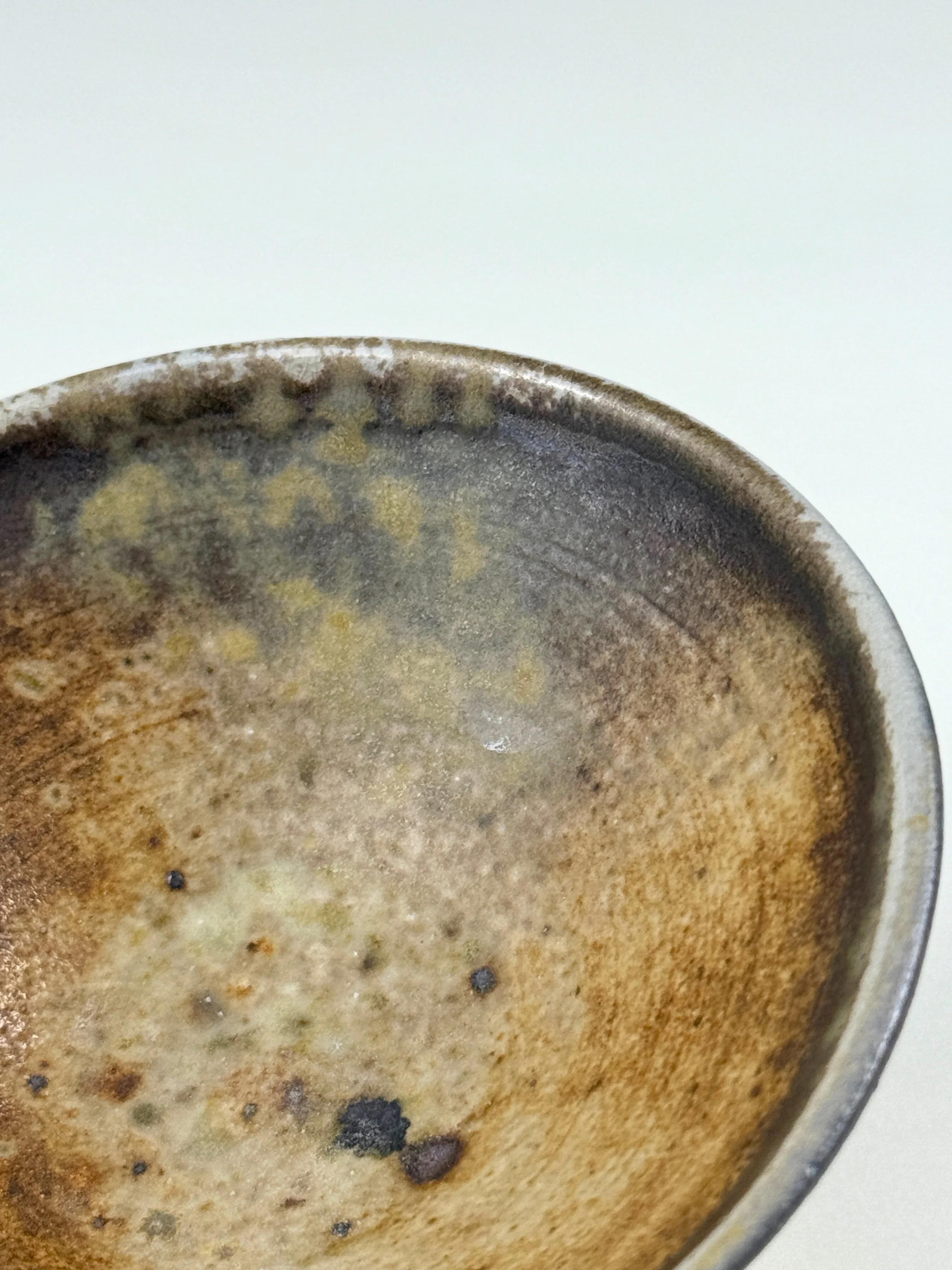 Close-up of the interior of a used ceramic coffee cup with brown and black stains.