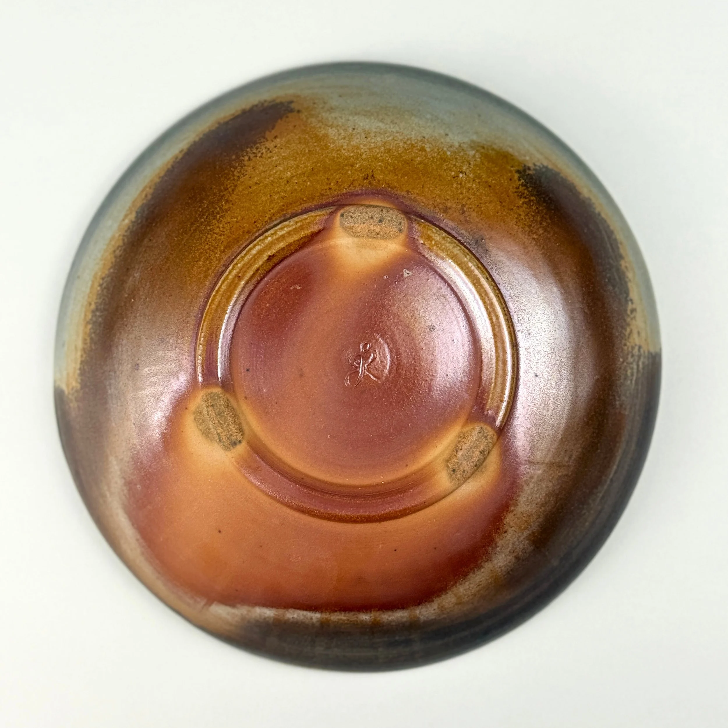 Close-up of the bottom of a glass bottle showing a circular indentation and rust or dirt residues around the edges.