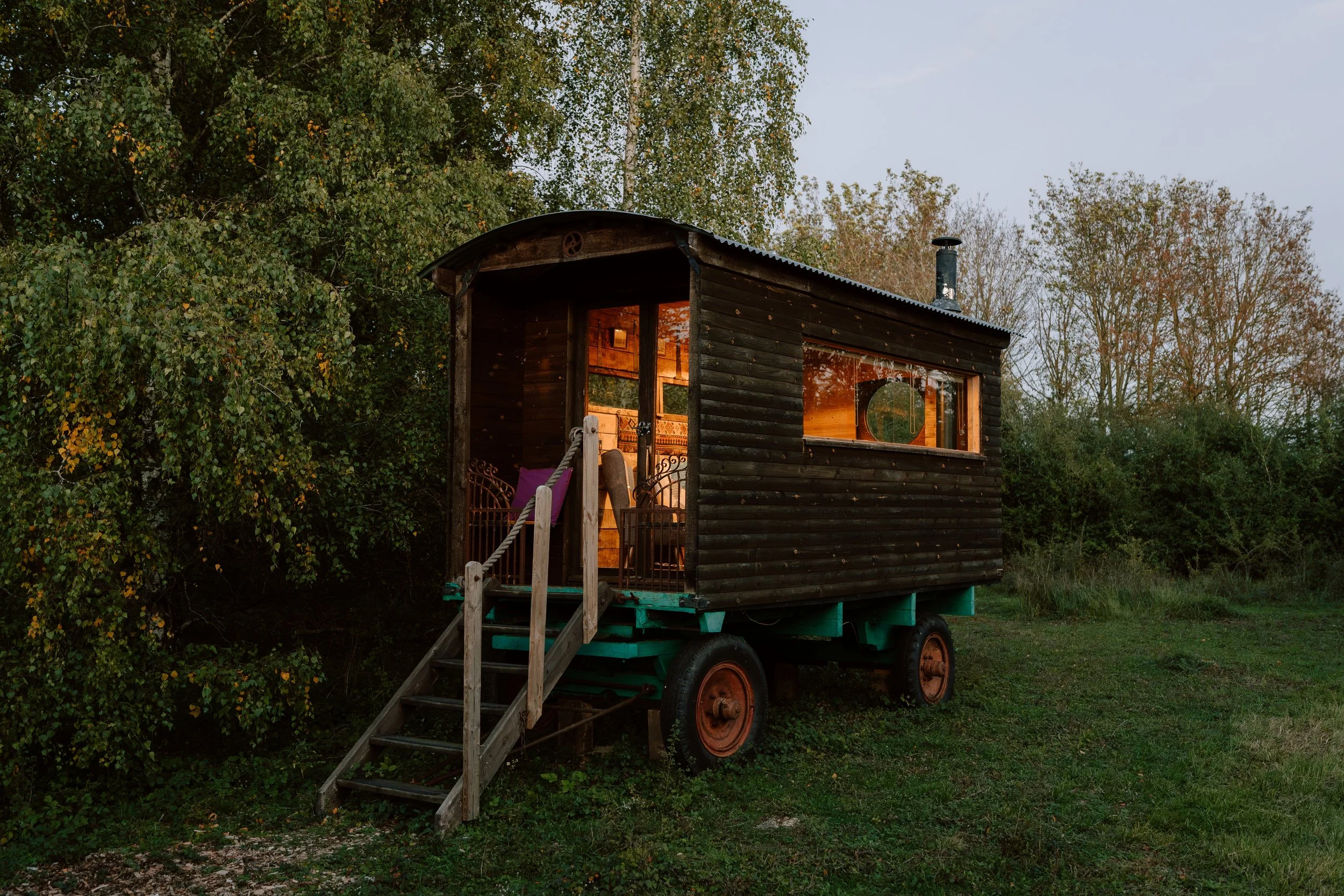 A shepherds hut caravan library at dusk with lit windows