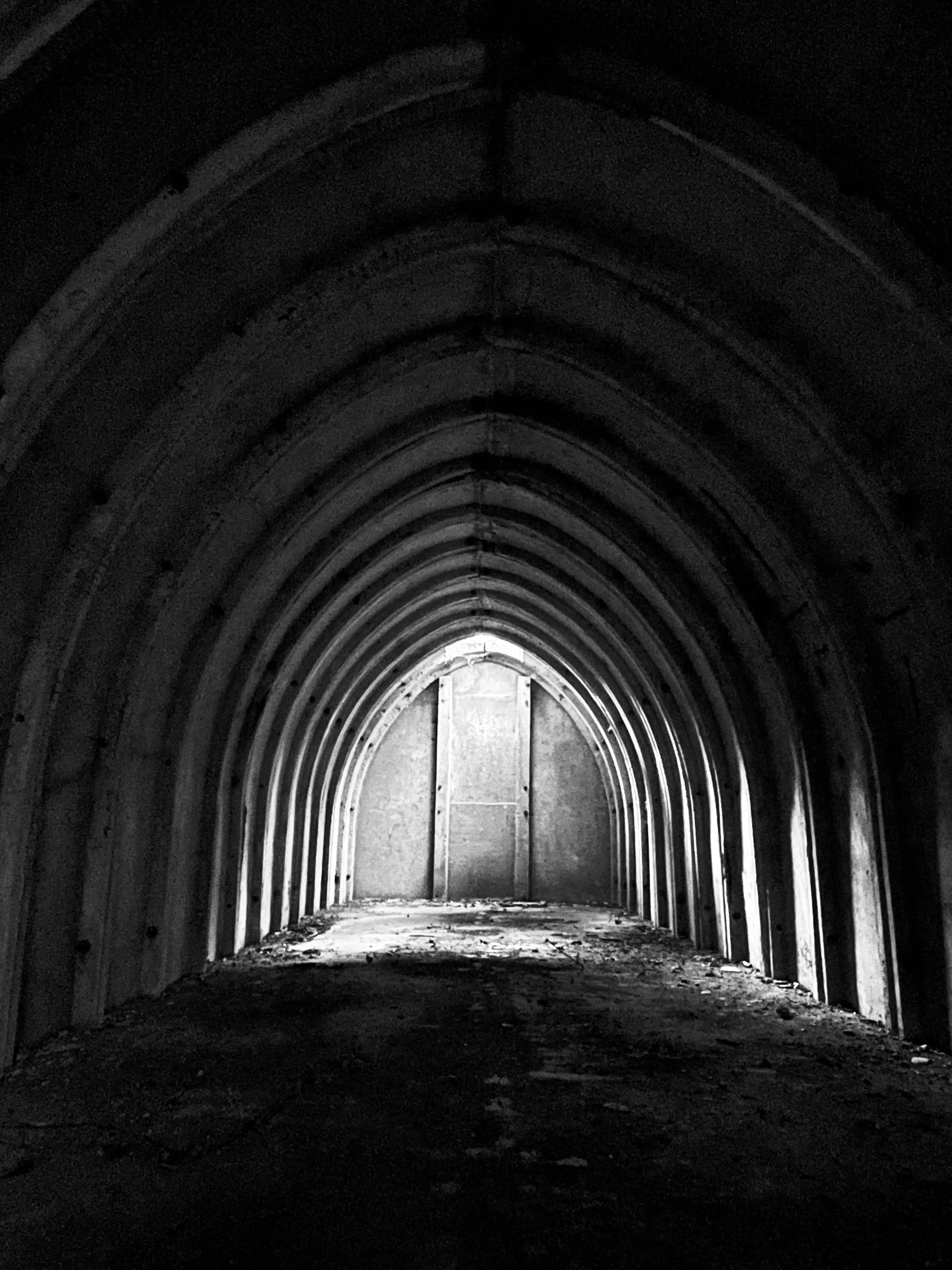 Stanton shelter type bunker with arched structure leading to a door at the end, illuminated by light from outside.