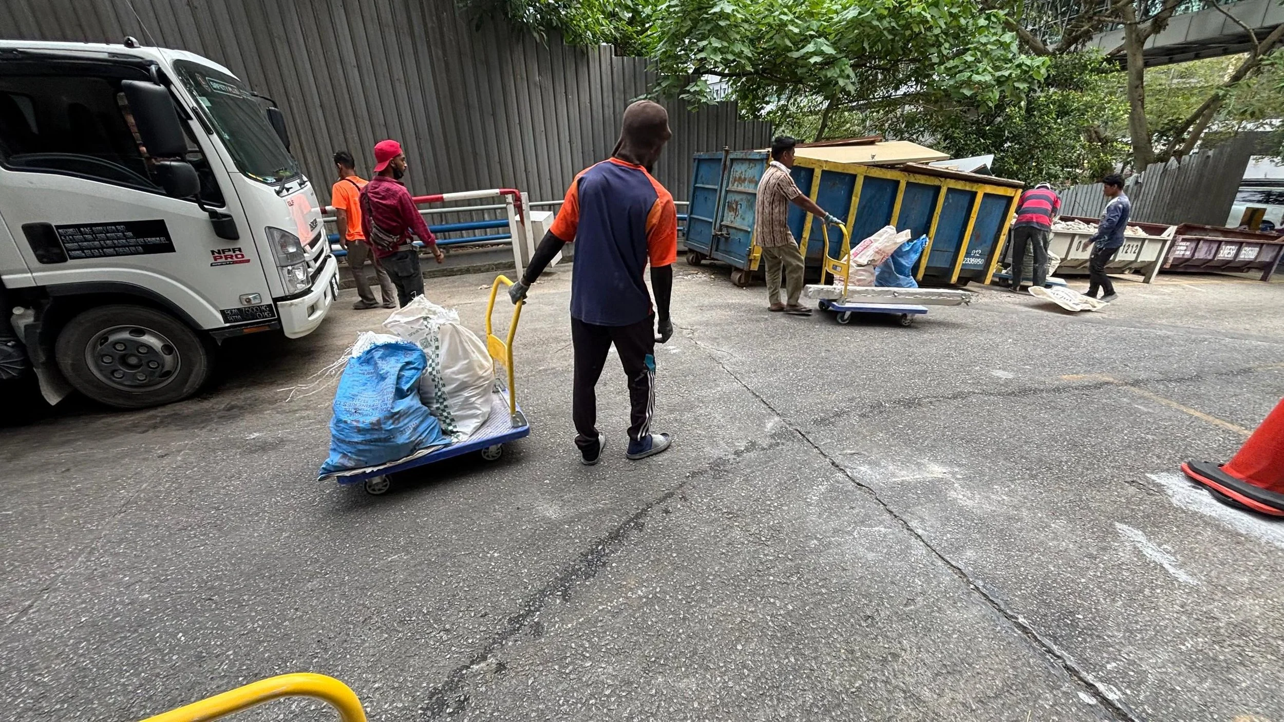 People working outside, unloading items from a truck and placing them into carts in an urban setting.