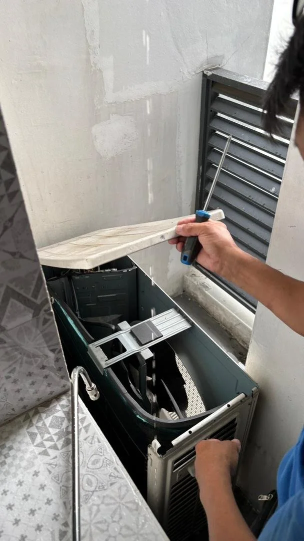 Person installing or repairing a computer or electronic device with a screwdriver in a small, enclosed workspace.