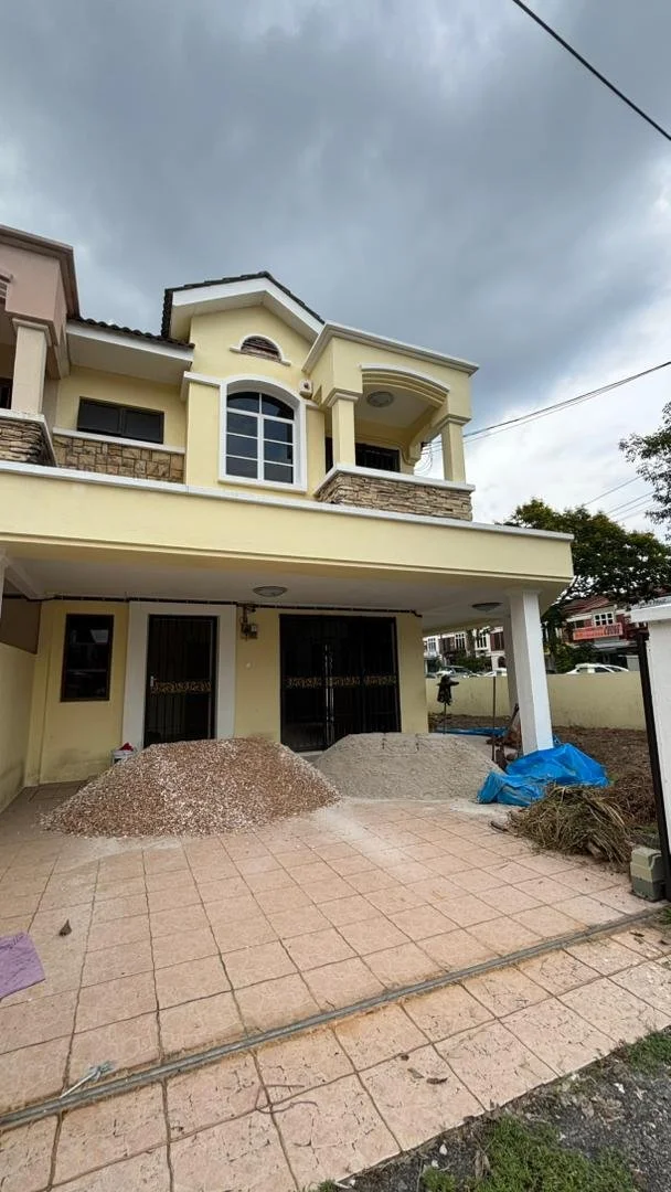 Construction and renovation service . Construction area in front of a yellow two-story house, with piles of gravel and sand, a blue tarp covering some materials, and an overcast sky.