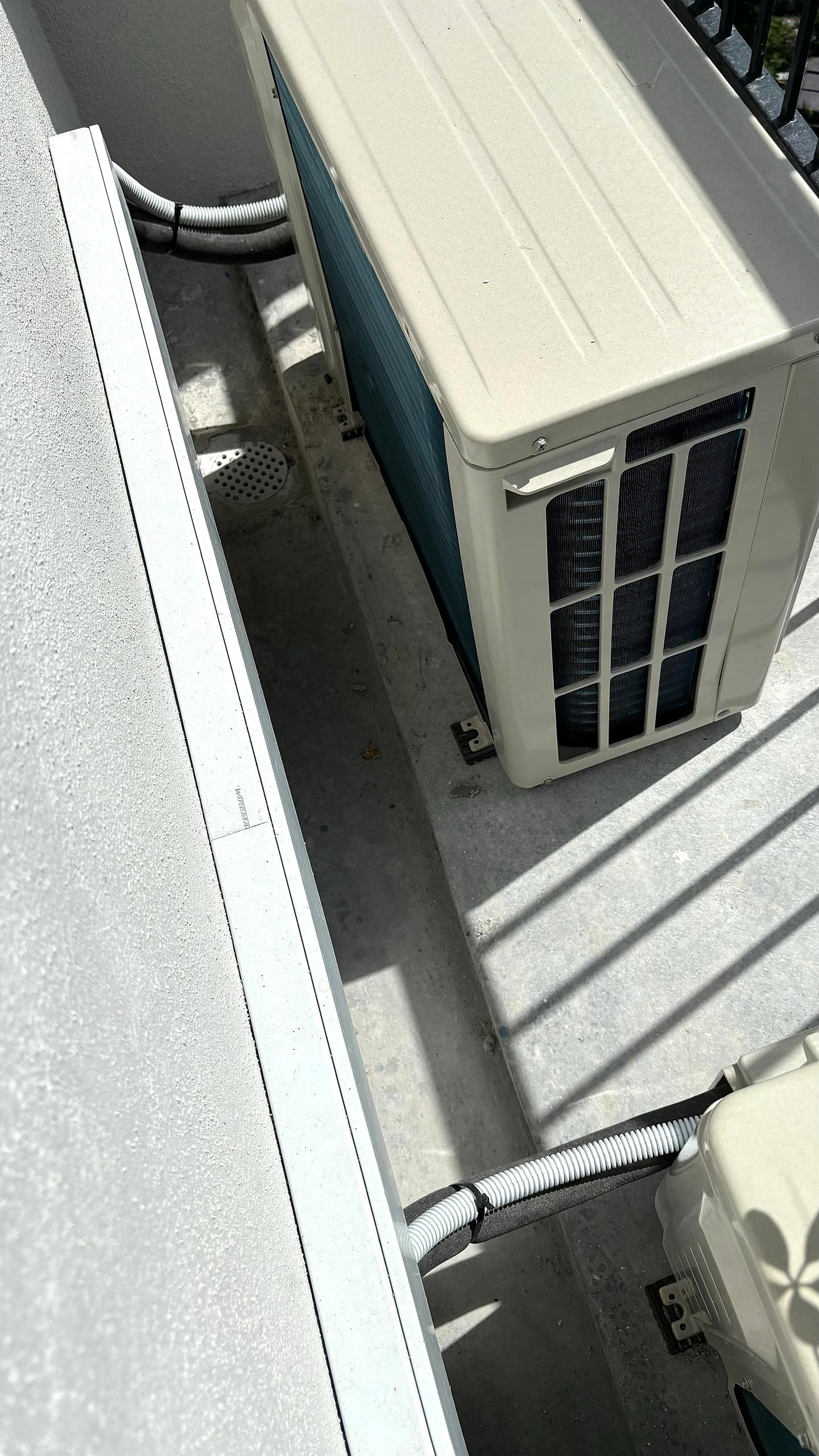 Outside view of an air conditioning unit and outdoor piping on a balcony or terrace