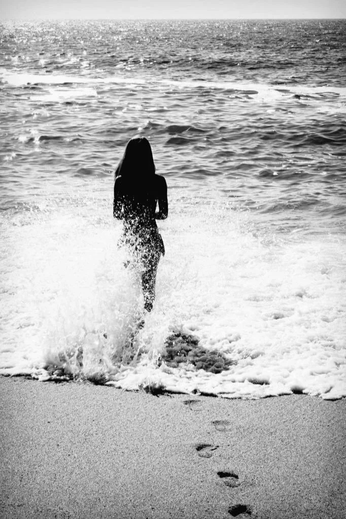 graphic of a women walking into the waves in the sea