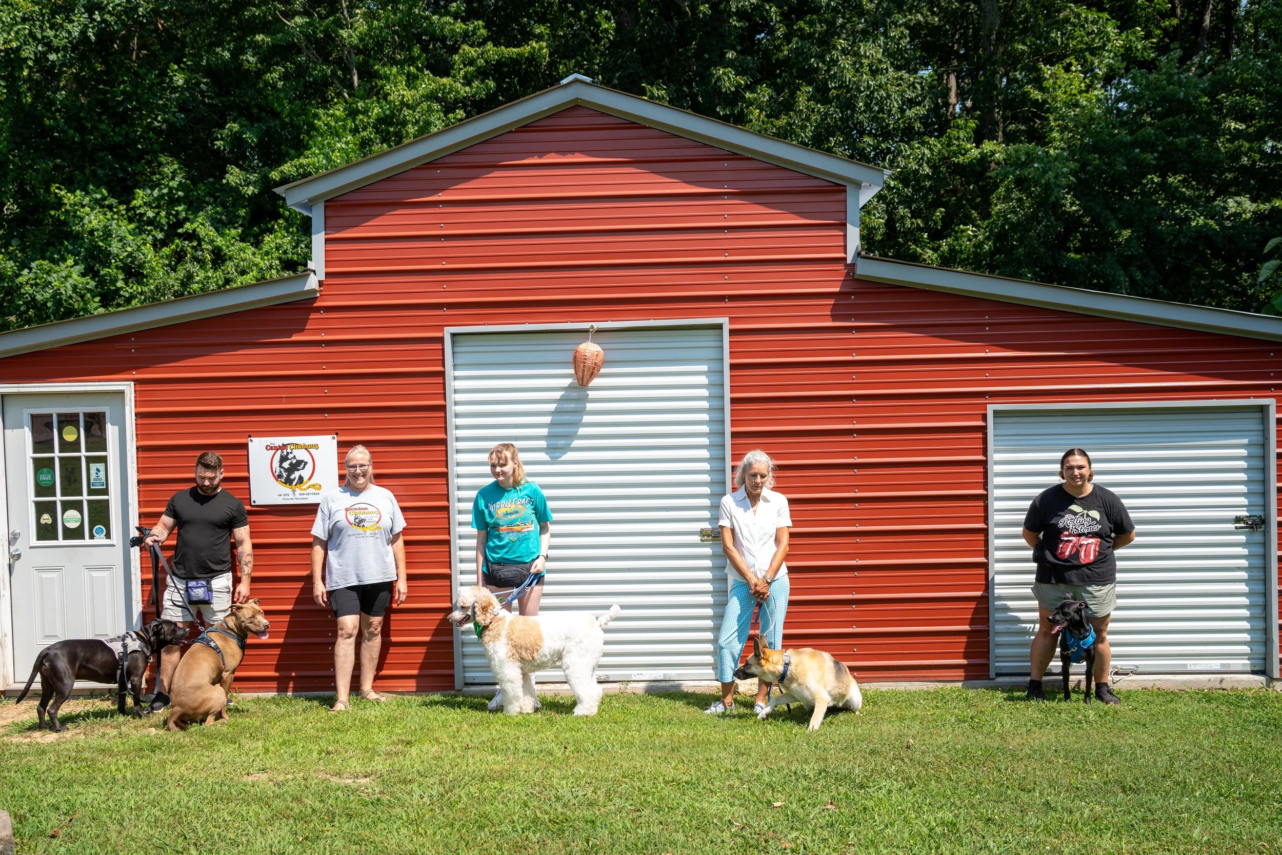 Students at The Canine Clubhaus looking at the camera after a group dog training session. FAQs